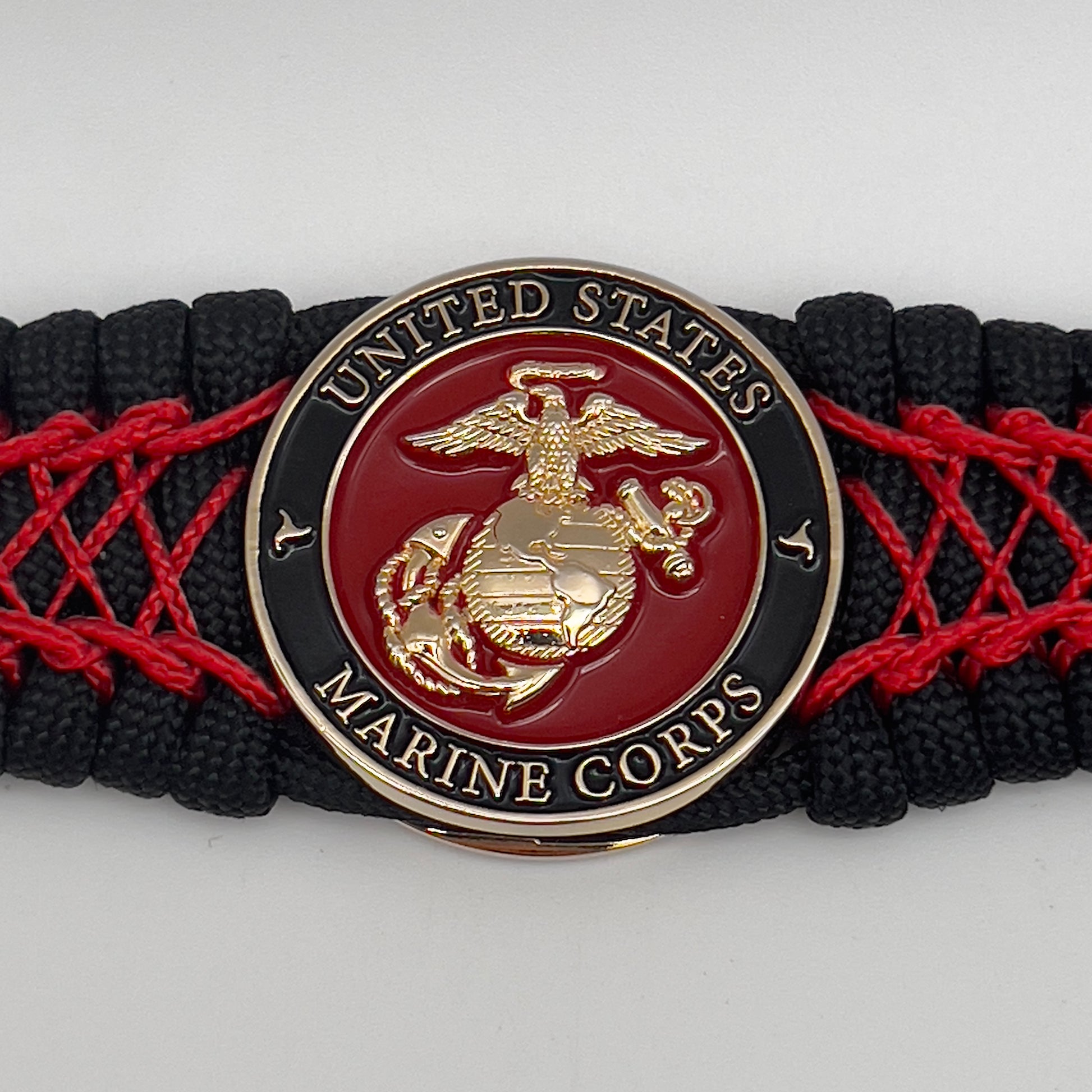Thick, wide, rigid and comfortable braided United States Marine Corps bracelet featuring a 24K gold plated USMC Eagle Globe and Anchor medallion, a black Cobra style tactical buckle and woven with black 550 paracord and Imperial Red nano and micro cord.