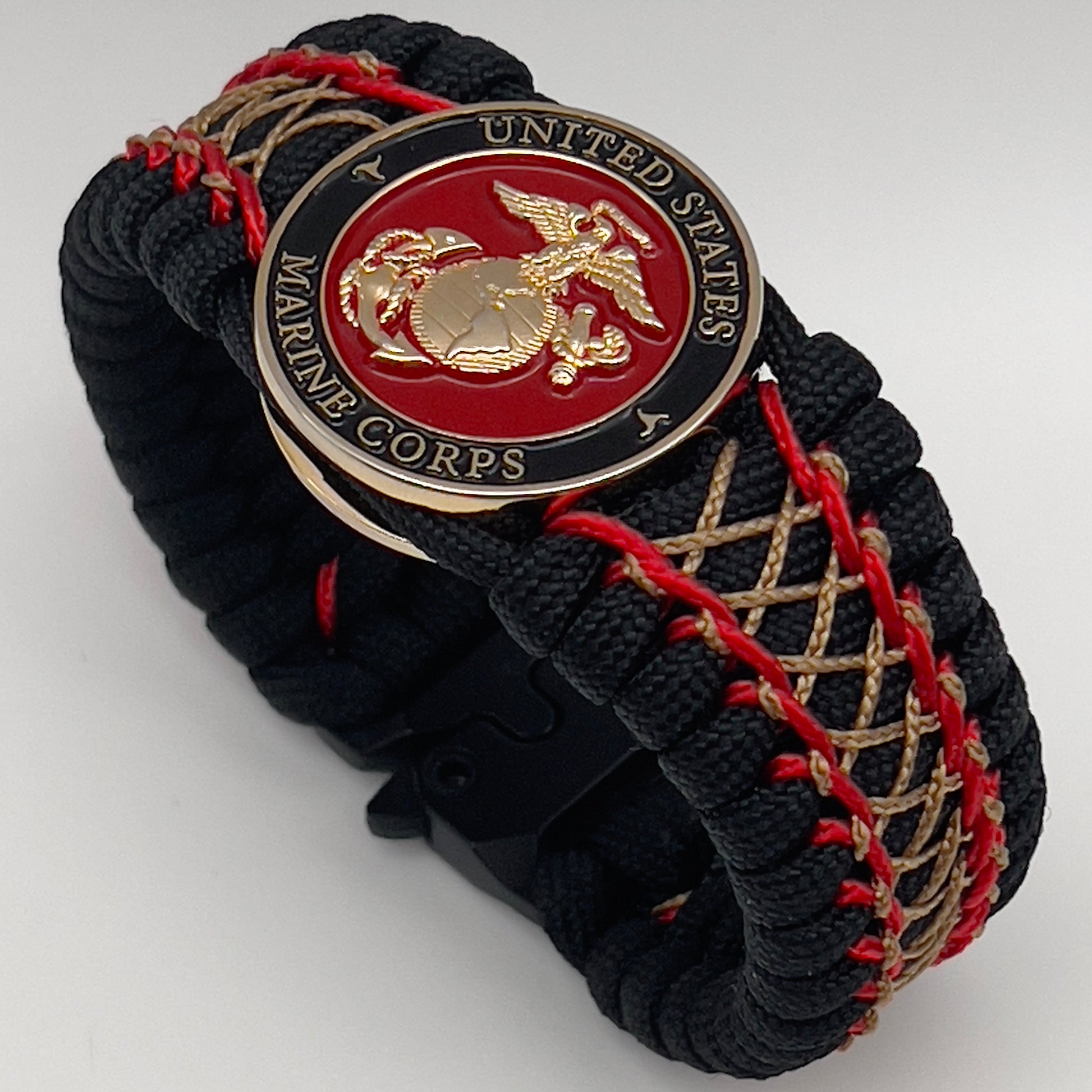 Thick, wide, rigid and comfortable braided United States Marine Corps bracelet featuring a 24K gold plated USMC Eagle Globe and Anchor medallion, a black Cobra style tactical buckle and woven with black 550 paracord and Imperial Red micro and gold nano cord.