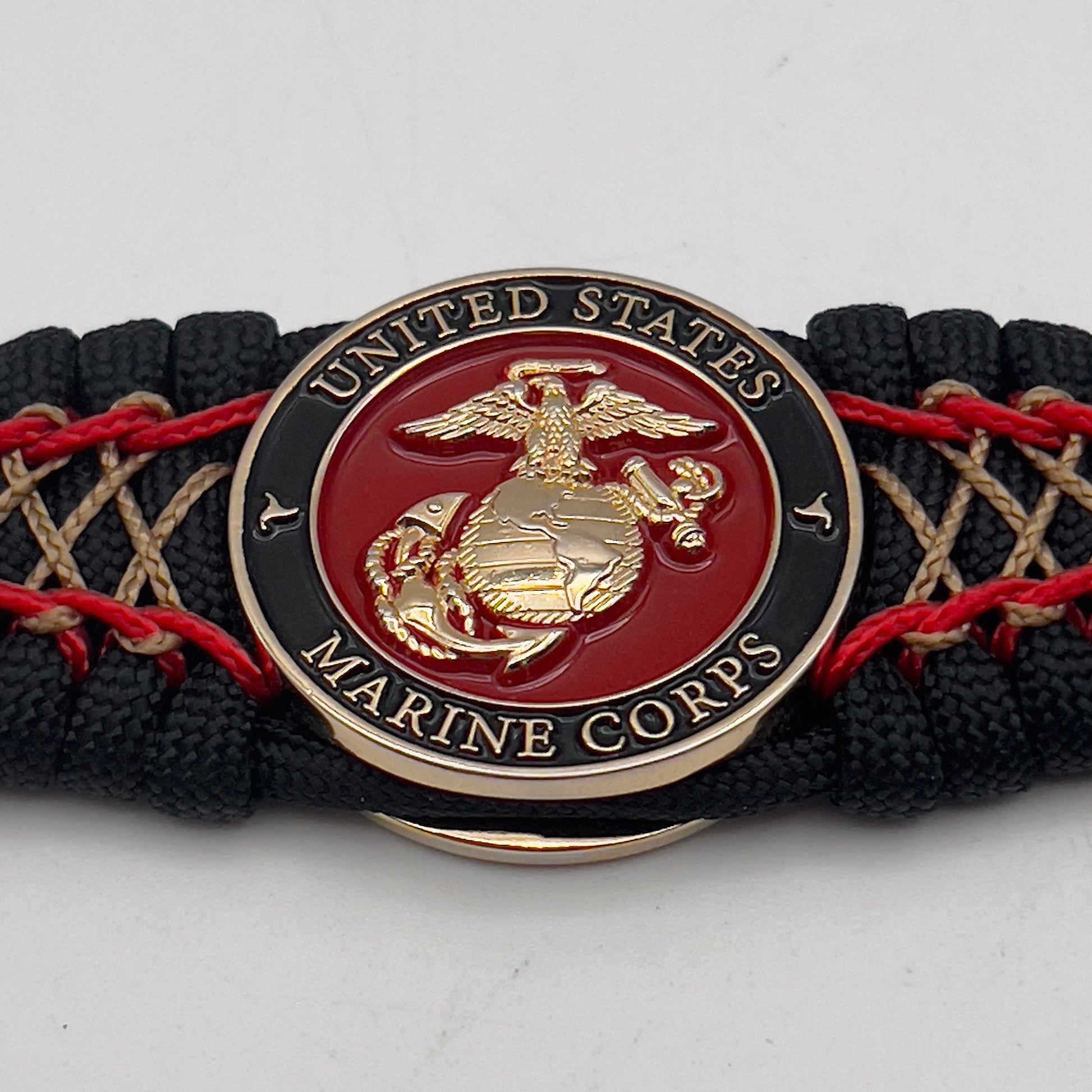 Thick, wide, rigid and comfortable braided United States Marine Corps bracelet featuring a 24K gold plated USMC Eagle Globe and Anchor medallion, a black Cobra style tactical buckle and woven with black 550 paracord and Imperial Red micro and gold nano cord.