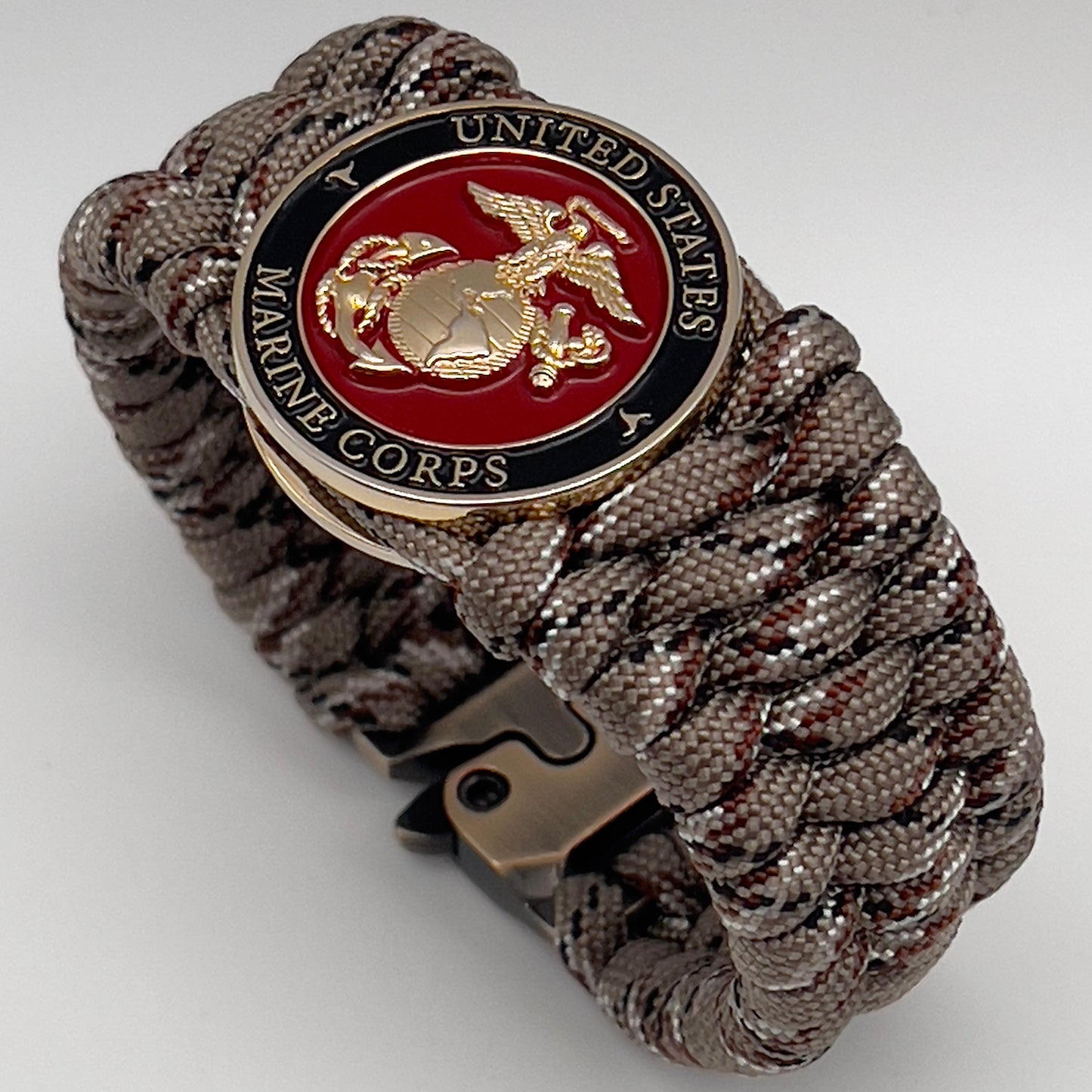 Thick, wide, semi-rigid and comfortable braided United States Marine Corps bracelet featuring a 24K gold plated USMC Eagle Globe and Anchor medallion, a gold Cobra style tactical buckle and woven with Desert Camo 550 paracord.