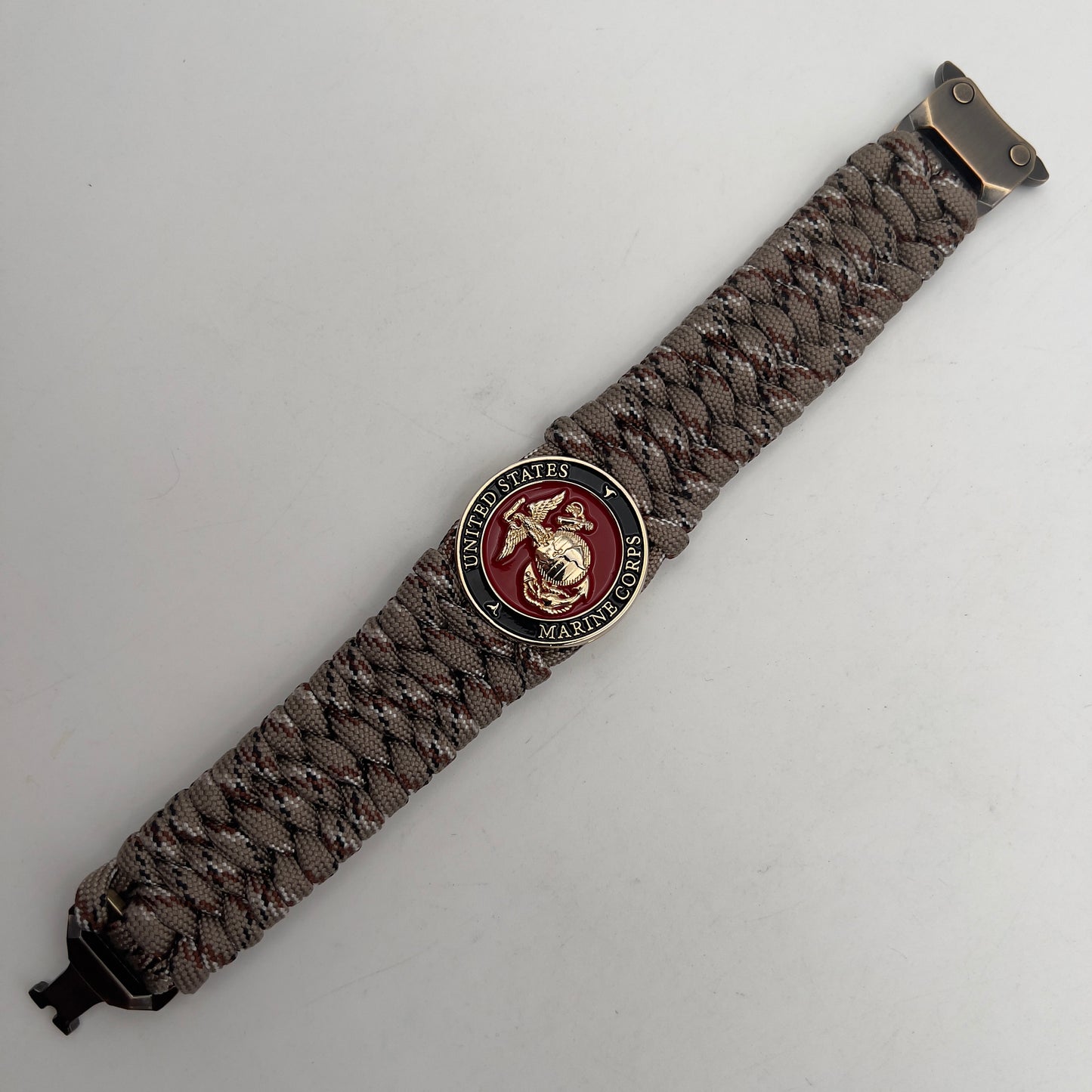 Thick, wide, semi-rigid and comfortable braided United States Marine Corps bracelet featuring a 24K gold plated USMC Eagle Globe and Anchor medallion, a gold Cobra style tactical buckle and woven with Desert Camo 550 paracord.