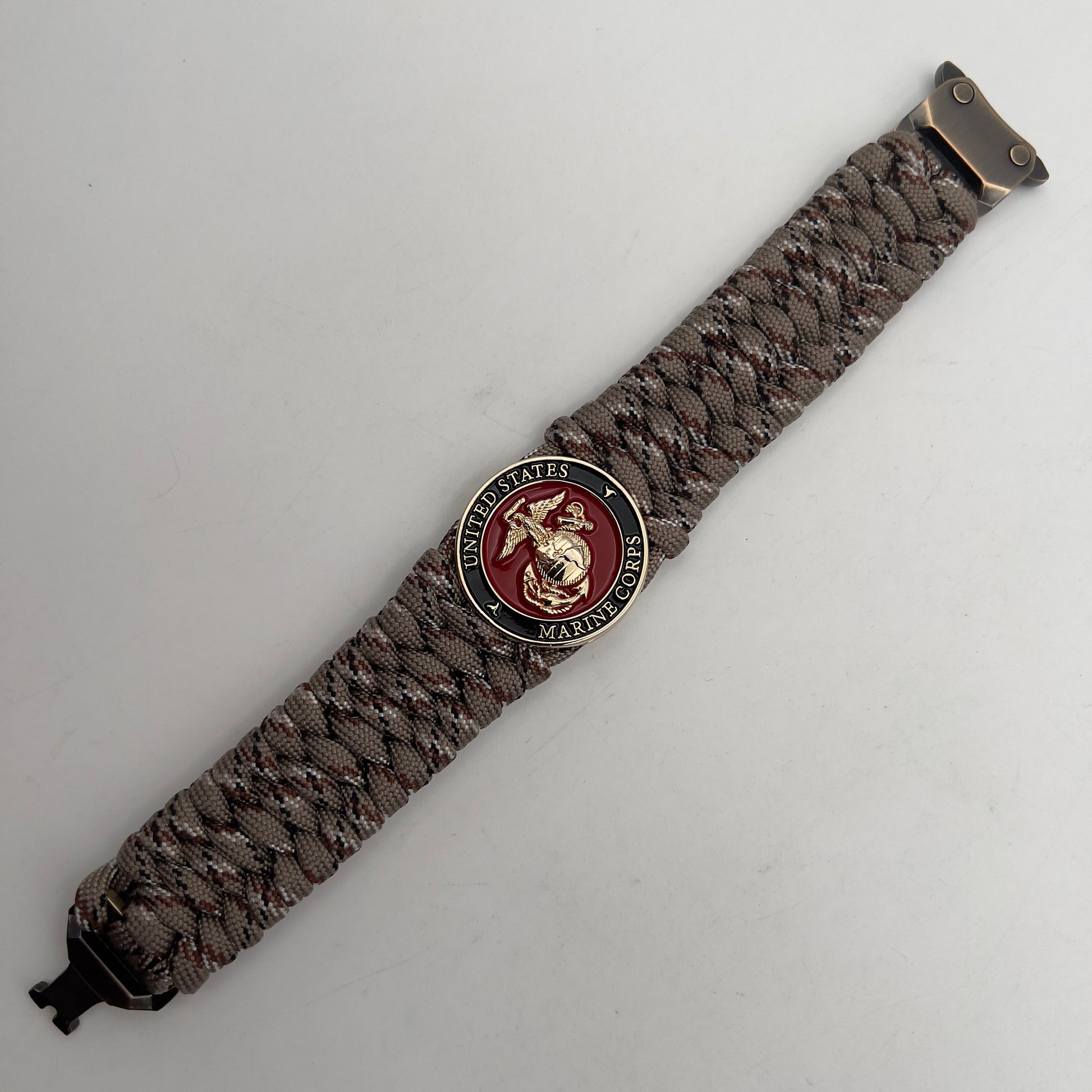 Thick, wide, semi-rigid and comfortable braided United States Marine Corps bracelet featuring a 24K gold plated USMC Eagle Globe and Anchor medallion, a gold Cobra style tactical buckle and woven with Desert Camo 550 paracord.