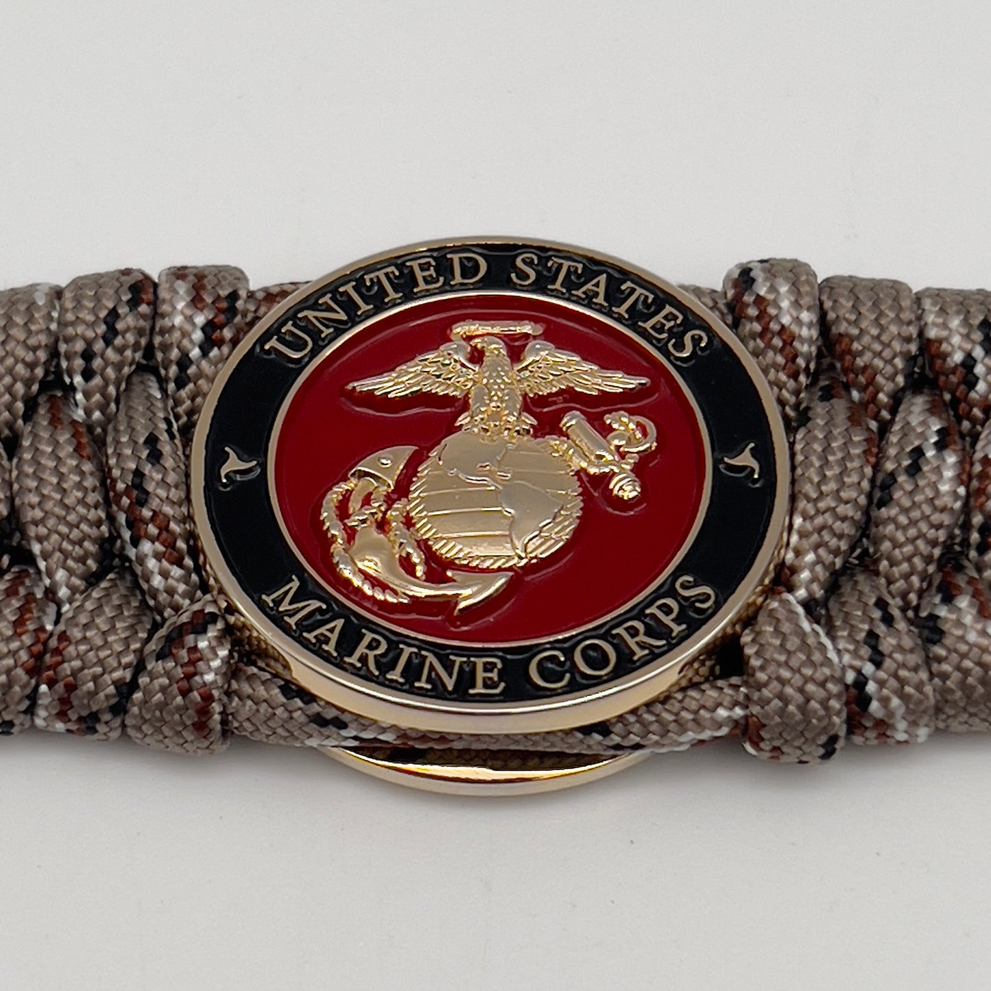 Thick, wide, semi-rigid and comfortable braided United States Marine Corps bracelet featuring a 24K gold plated USMC Eagle Globe and Anchor medallion, a gold Cobra style tactical buckle and woven with Desert Camo 550 paracord.