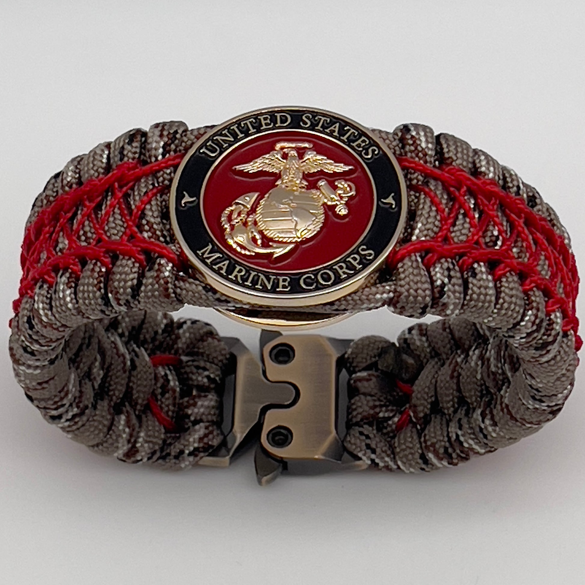 Thick, wide, rigid and comfortable braided United States Marine Corps bracelet featuring a 24K gold plated USMC Eagle Globe and Anchor medallion, a gold Cobra style tactical buckle and woven with Desert Camo 550 paracord and Imperial Red nano and micro cord.
