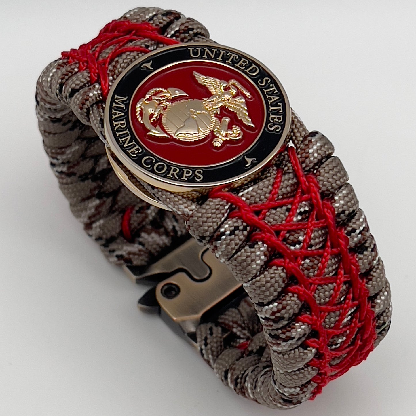 Thick, wide, rigid and comfortable braided United States Marine Corps bracelet featuring a 24K gold plated USMC Eagle Globe and Anchor medallion, a gold Cobra style tactical buckle and woven with Desert Camo 550 paracord and Imperial Red nano and micro cord.
