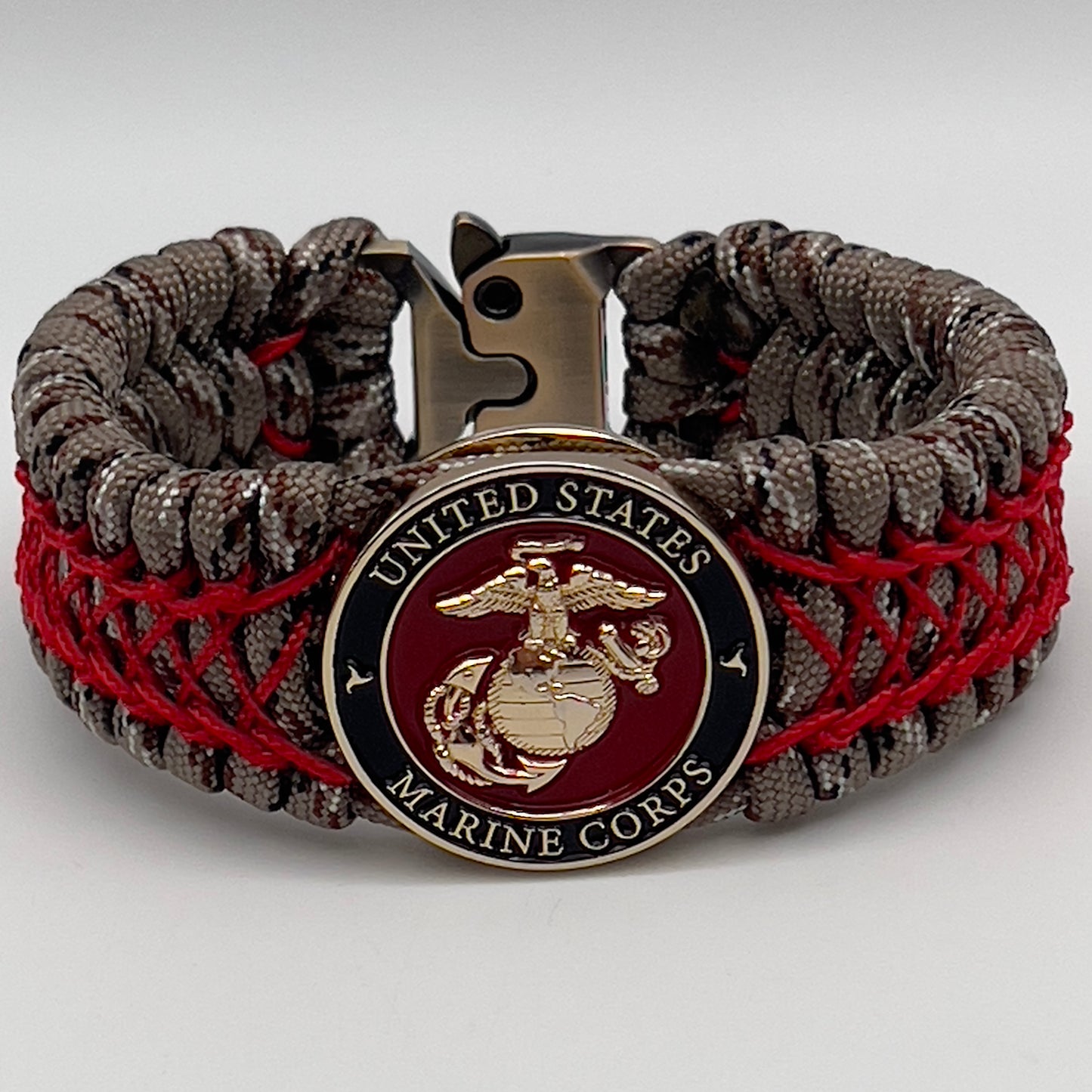Thick, wide, rigid and comfortable braided United States Marine Corps bracelet featuring a 24K gold plated USMC Eagle Globe and Anchor medallion, a gold Cobra style tactical buckle and woven with Desert Camo 550 paracord and Imperial Red nano and micro cord.