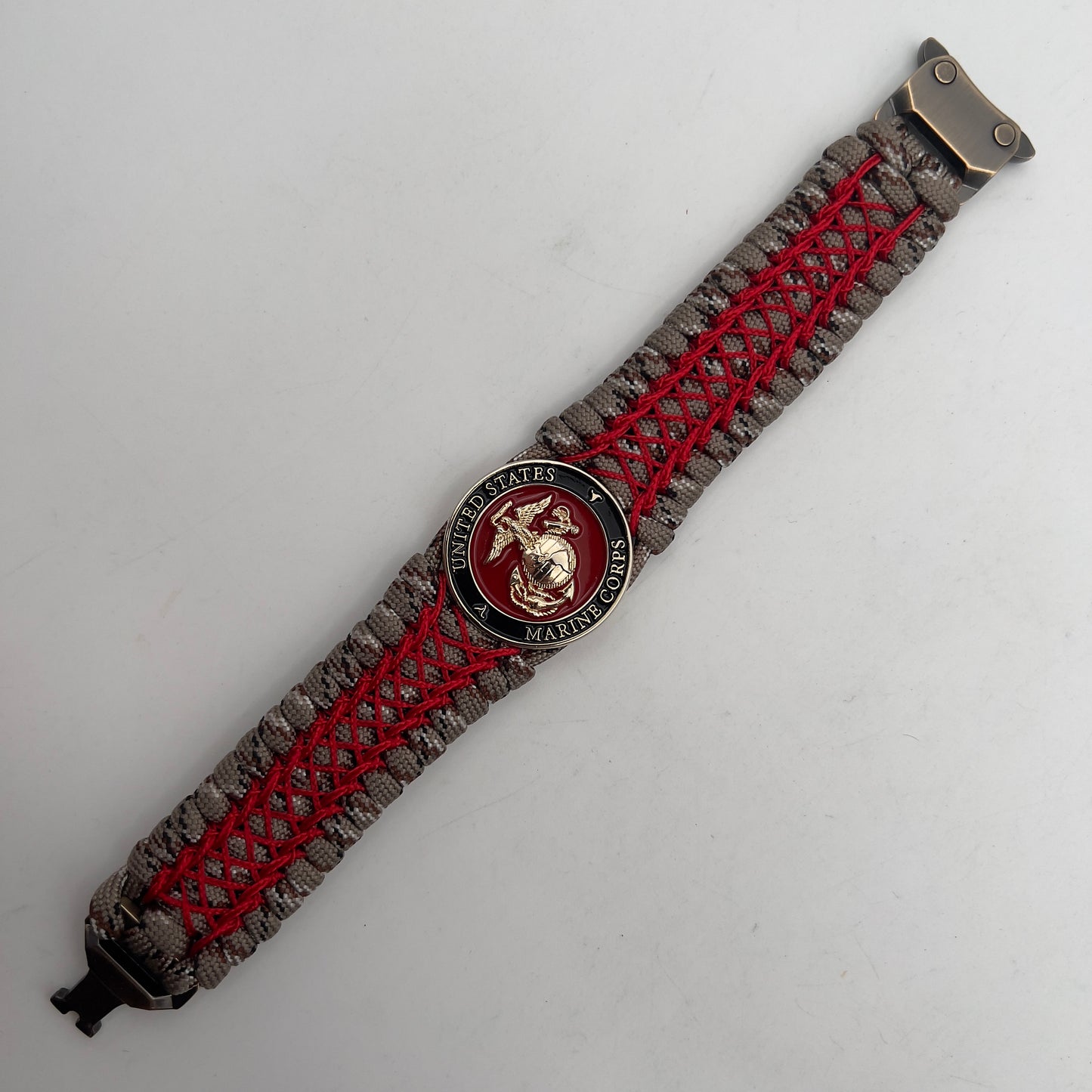 Thick, wide, rigid and comfortable braided United States Marine Corps bracelet featuring a 24K gold plated USMC Eagle Globe and Anchor medallion, a gold Cobra style tactical buckle and woven with Desert Camo 550 paracord and Imperial Red nano and micro cord.