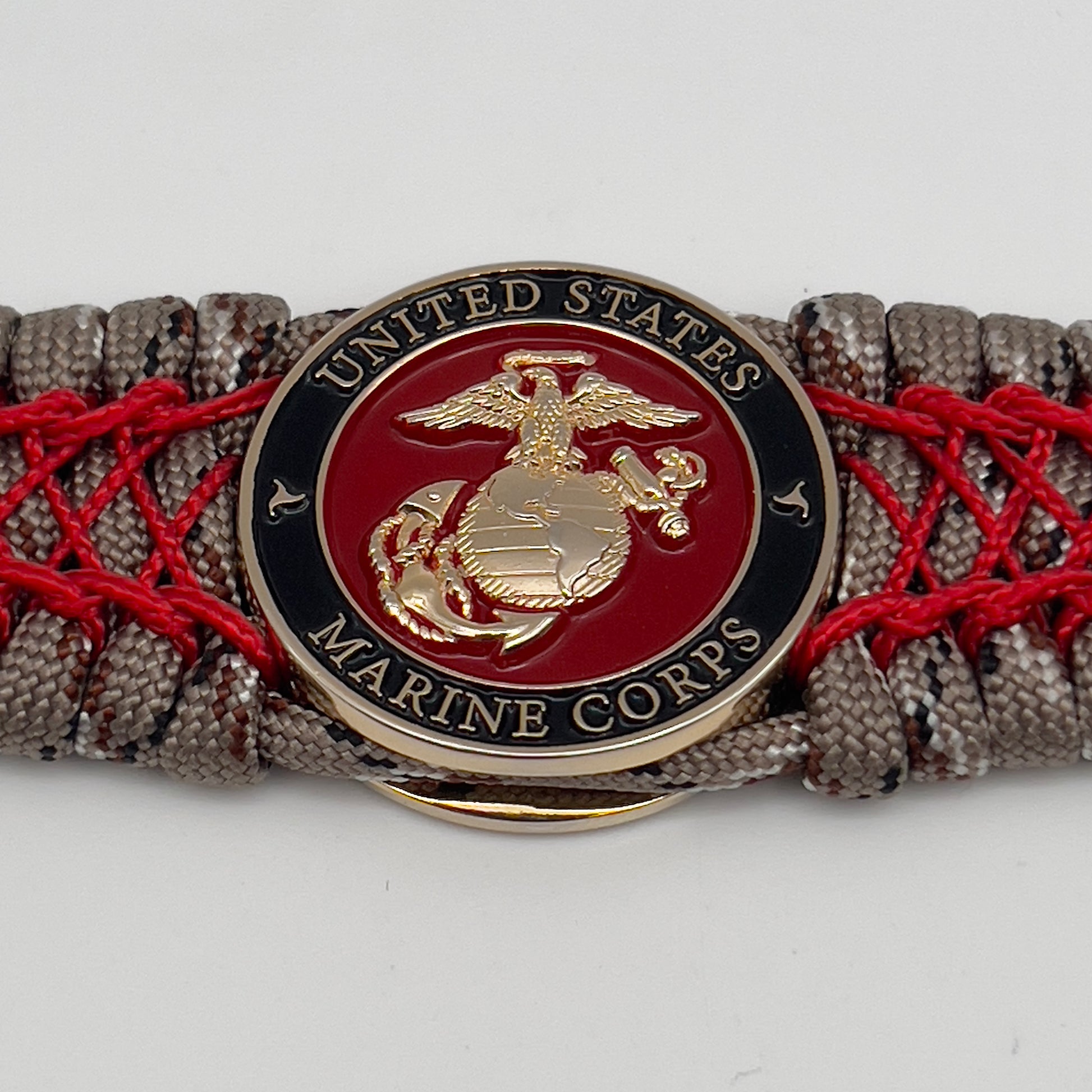 Thick, wide, rigid and comfortable braided United States Marine Corps bracelet featuring a 24K gold plated USMC Eagle Globe and Anchor medallion, a gold Cobra style tactical buckle and woven with Desert Camo 550 paracord and Imperial Red nano and micro cord.