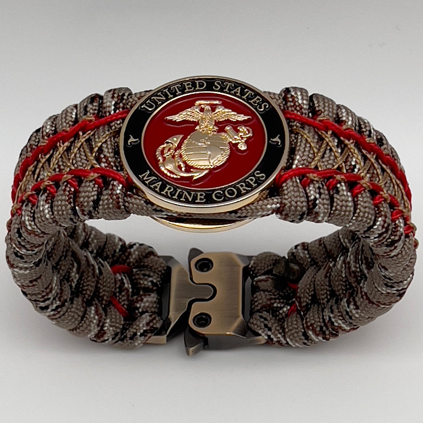 Thick, wide, rigid and comfortable braided United States Marine Corps bracelet featuring a 24K gold plated USMC Eagle Globe and Anchor medallion, a gold Cobra style tactical buckle and woven with Desert Camo 550 paracord and Imperial Red micro and gold nano cord.