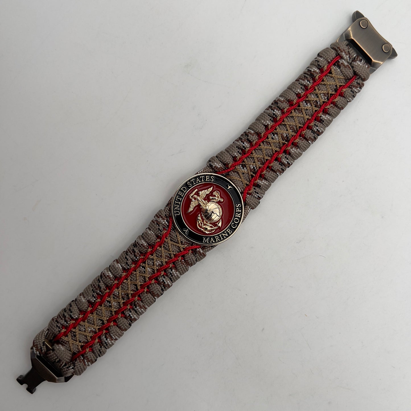 Thick, wide, rigid and comfortable braided United States Marine Corps bracelet featuring a 24K gold plated USMC Eagle Globe and Anchor medallion, a gold Cobra style tactical buckle and woven with Desert Camo 550 paracord and Imperial Red micro and gold nano cord.