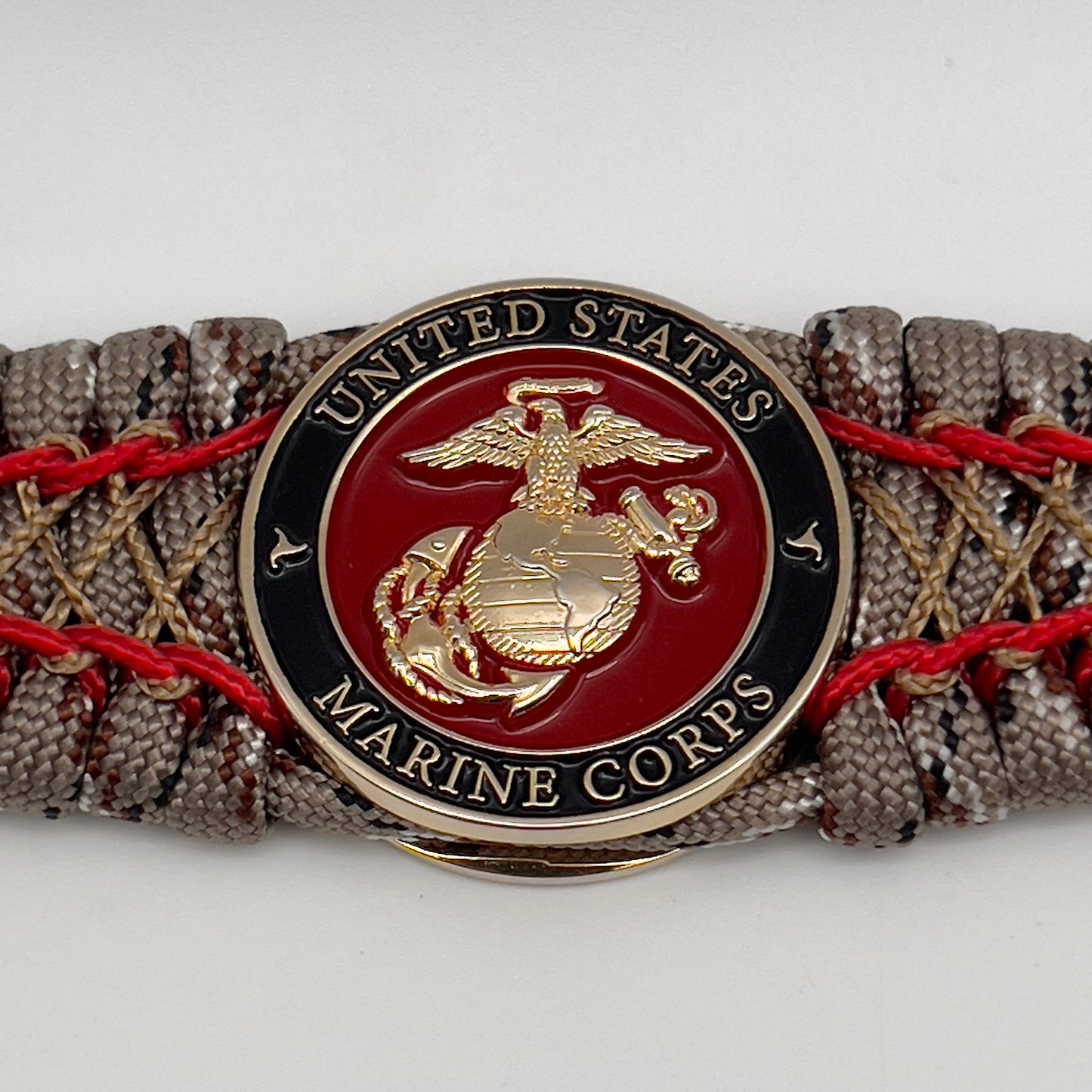 Thick, wide, rigid and comfortable braided United States Marine Corps bracelet featuring a 24K gold plated USMC Eagle Globe and Anchor medallion, a gold Cobra style tactical buckle and woven with Desert Camo 550 paracord and Imperial Red micro and gold nano cord.