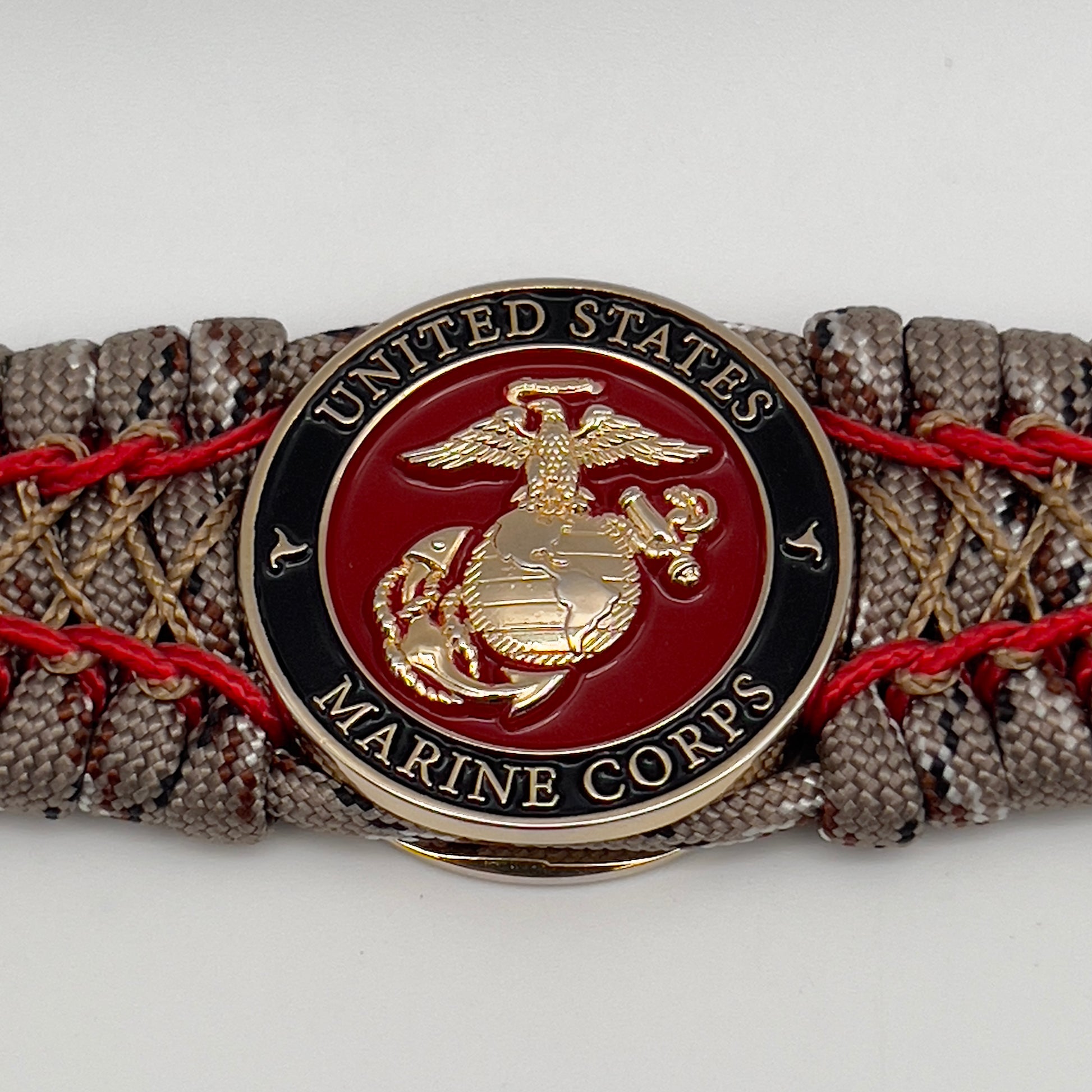 Thick, wide, rigid and comfortable braided United States Marine Corps bracelet featuring a 24K gold plated USMC Eagle Globe and Anchor medallion, a gold Cobra style tactical buckle and woven with Desert Camo 550 paracord and Imperial Red micro and gold nano cord.