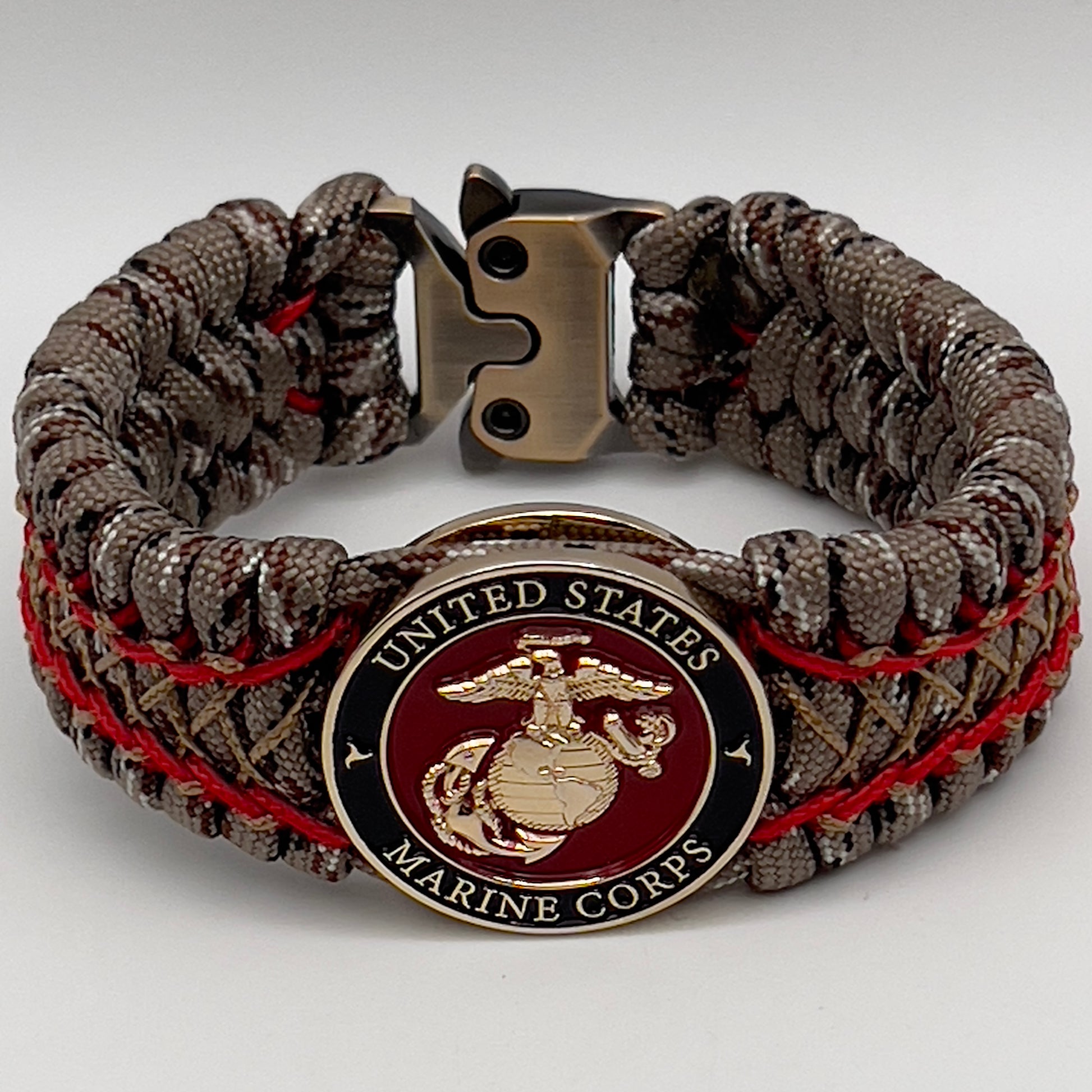 Thick, wide, rigid and comfortable braided United States Marine Corps bracelet featuring a 24K gold plated USMC Eagle Globe and Anchor medallion, a gold Cobra style tactical buckle and woven with Desert Camo 550 paracord and Imperial Red micro and gold nano cord.