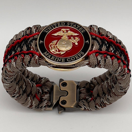 Thick, wide, rigid and comfortable braided United States Marine Corps bracelet featuring a 24K gold plated USMC Eagle Globe and Anchor medallion, a gold Cobra style tactical buckle and woven with Desert Camo 550 paracord, Imperial Red micro cord and black nano cord.