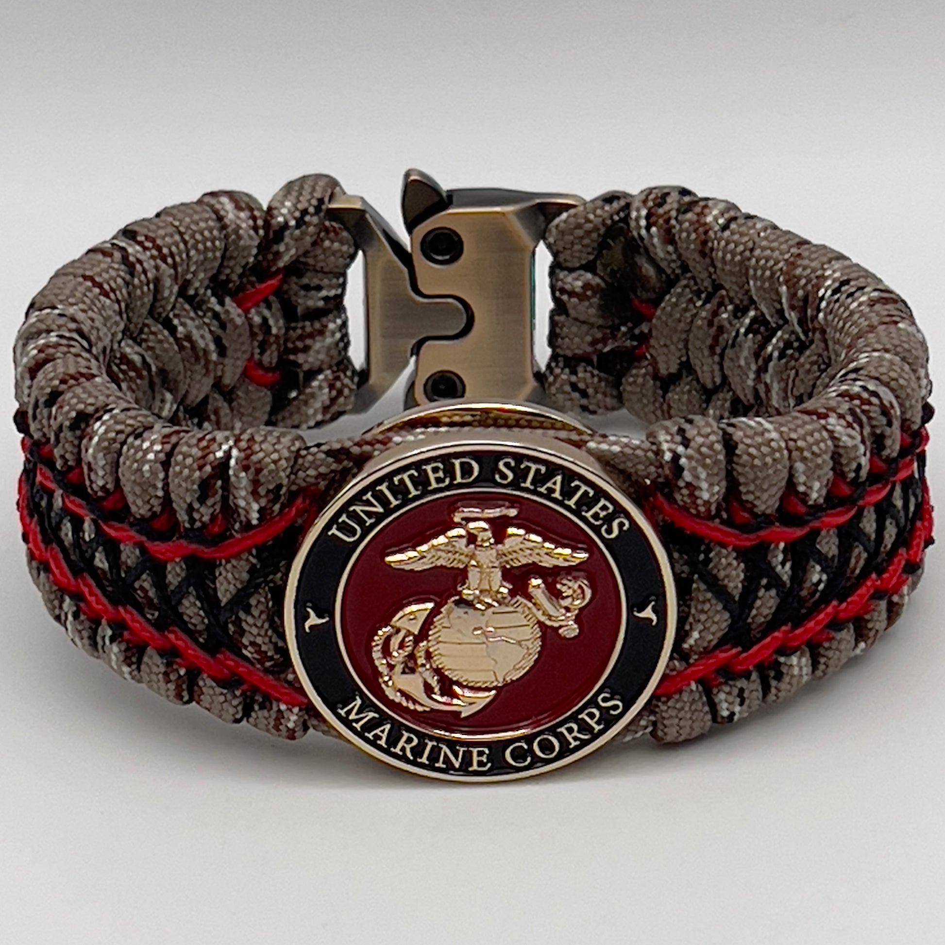 Thick, wide, rigid and comfortable braided United States Marine Corps bracelet featuring a 24K gold plated USMC Eagle Globe and Anchor medallion, a gold Cobra style tactical buckle and woven with Desert Camo 550 paracord, Imperial Red micro cord and black nano cord.