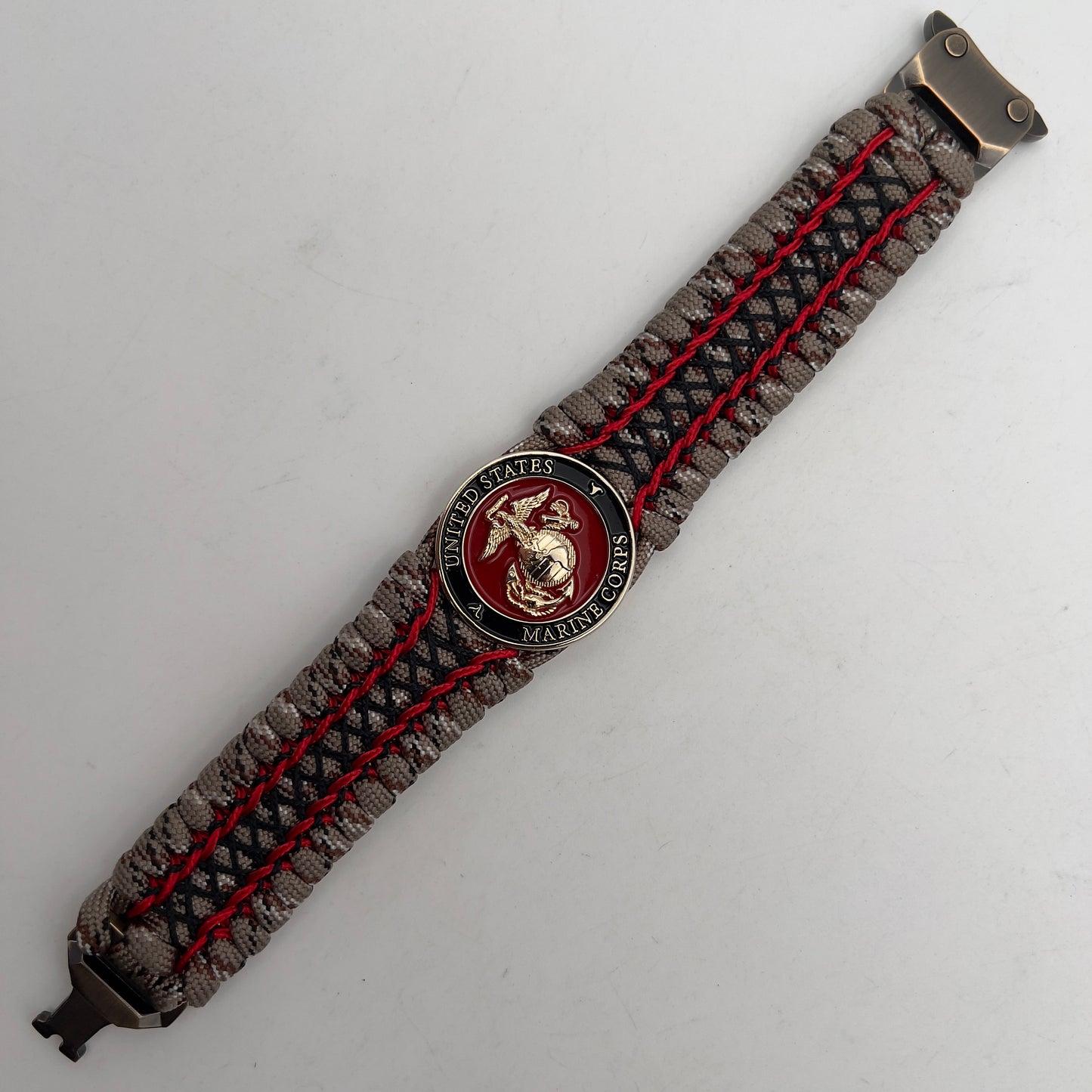 Thick, wide, rigid and comfortable braided United States Marine Corps bracelet featuring a 24K gold plated USMC Eagle Globe and Anchor medallion, a gold Cobra style tactical buckle and woven with Desert Camo 550 paracord, Imperial Red micro cord and black nano cord.