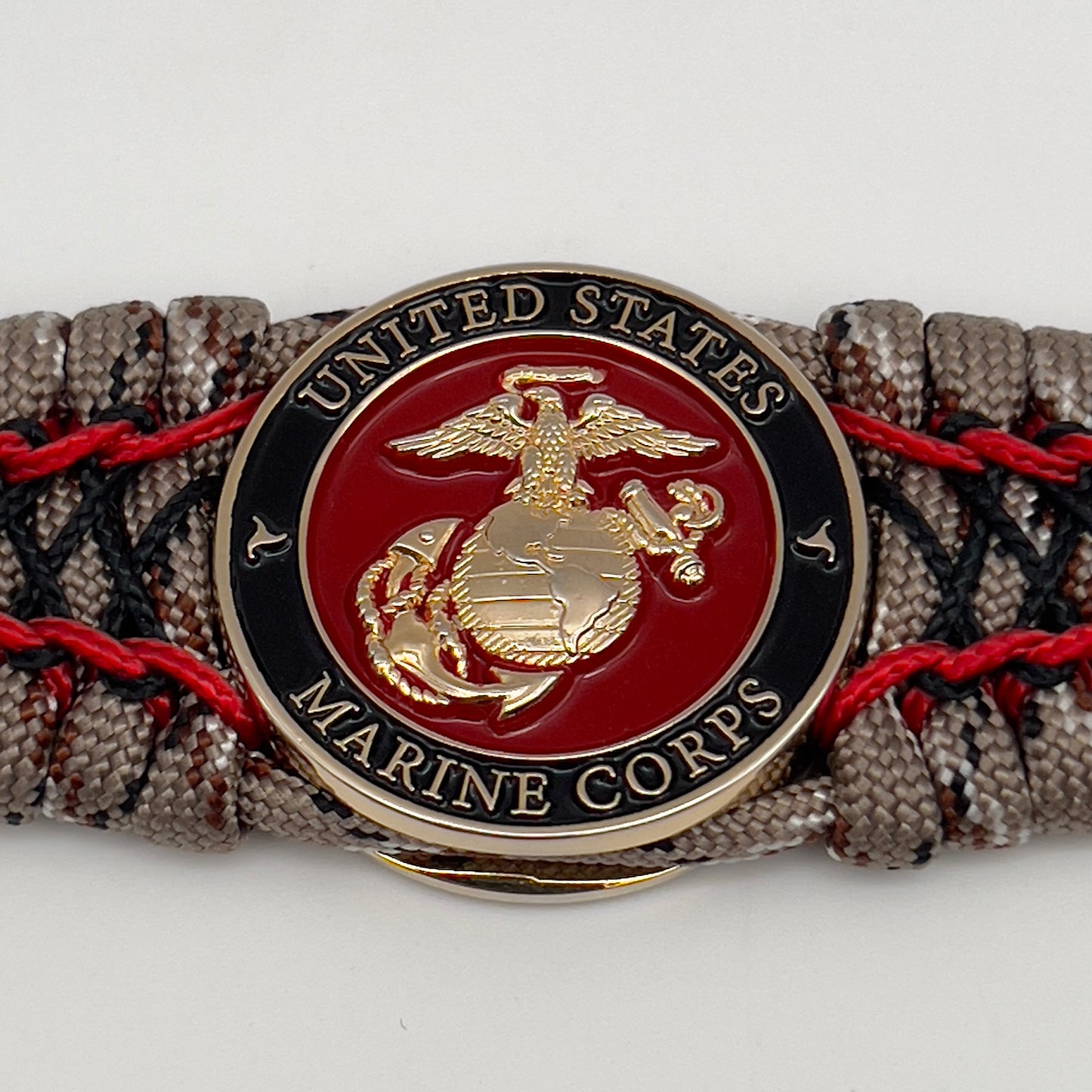 Thick, wide, rigid and comfortable braided United States Marine Corps bracelet featuring a 24K gold plated USMC Eagle Globe and Anchor medallion, a gold Cobra style tactical buckle and woven with Desert Camo 550 paracord, Imperial Red micro cord and black nano cord.