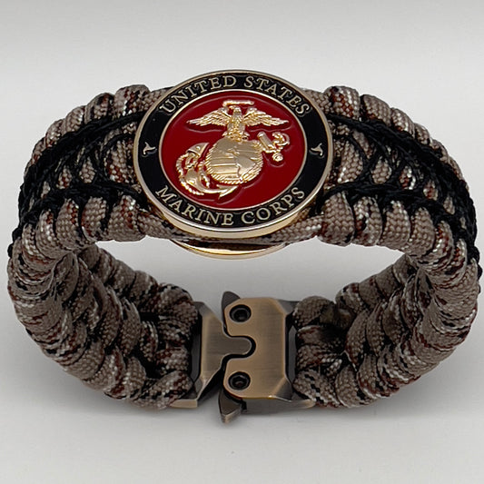 Thick, wide, rigid and comfortable braided United States Marine Corps bracelet featuring a 24K gold plated USMC Eagle Globe and Anchor medallion, a gold Cobra style tactical buckle and woven with Desert Camo 550 paracord and black nano and micro cord.