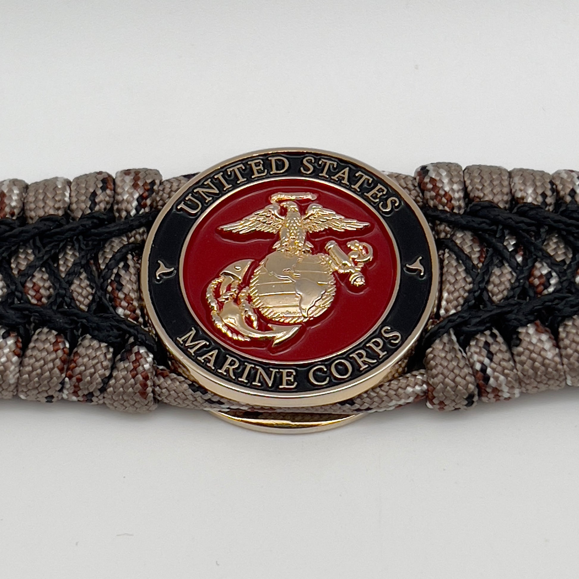 Thick, wide, rigid and comfortable braided United States Marine Corps bracelet featuring a 24K gold plated USMC Eagle Globe and Anchor medallion, a gold Cobra style tactical buckle and woven with Desert Camo 550 paracord and black nano and micro cord.
