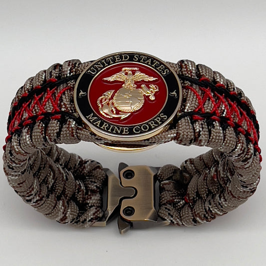 Thick, wide, rigid and comfortable braided United States Marine Corps bracelet featuring a 24K gold plated USMC Eagle Globe and Anchor medallion, a gold Cobra style tactical buckle and woven with Desert Camo 550 paracord, black micro cord and Imperial Red nano cord.