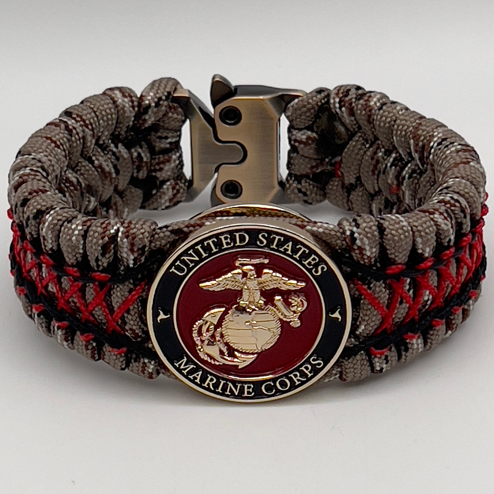 Thick, wide, rigid and comfortable braided United States Marine Corps bracelet featuring a 24K gold plated USMC Eagle Globe and Anchor medallion, a gold Cobra style tactical buckle and woven with Desert Camo 550 paracord, black micro cord and Imperial Red nano cord.