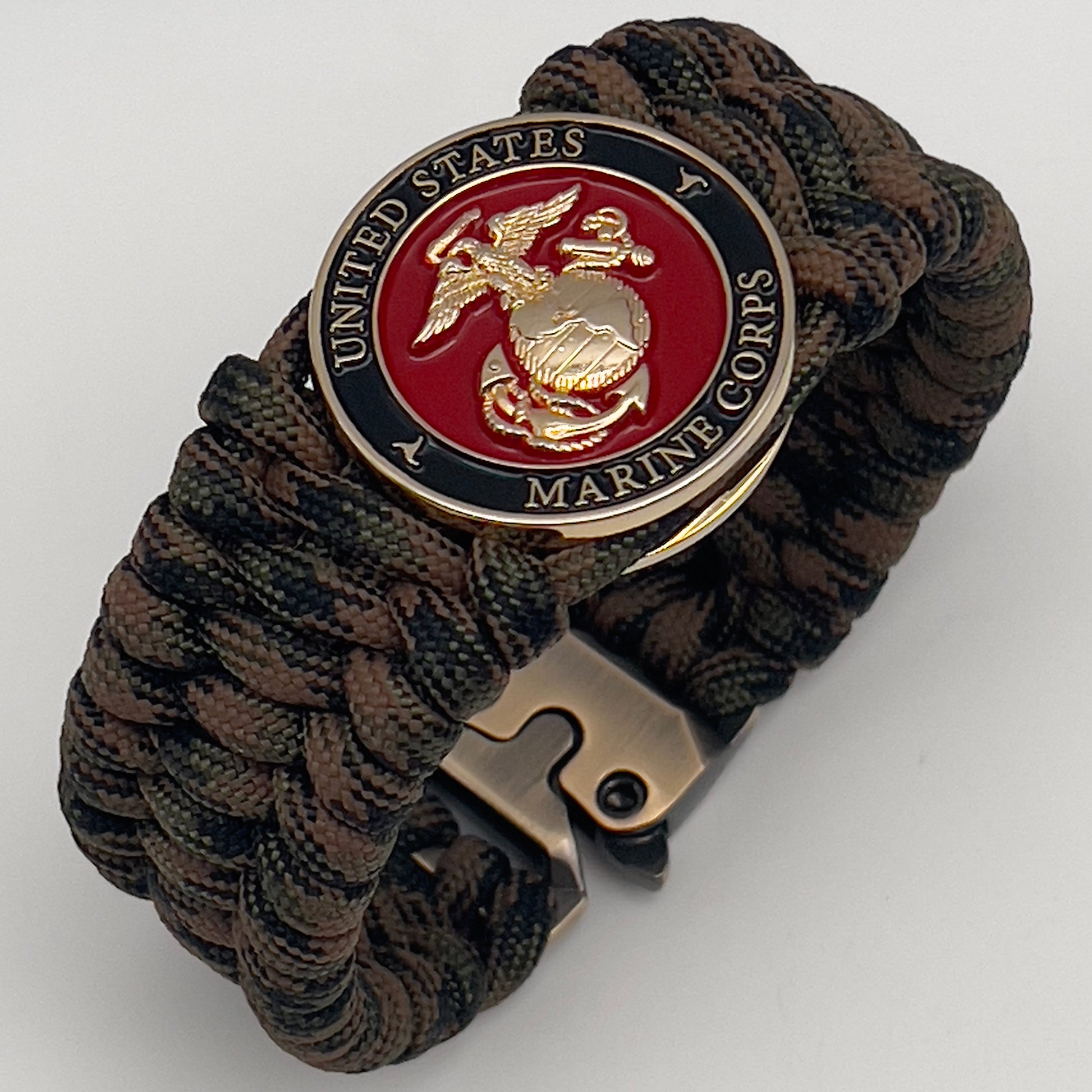 Thick, wide, semi-rigid and comfortable braided United States Marine Corps bracelet featuring a 24K gold plated USMC Eagle Globe and Anchor medallion, a gold Cobra style tactical buckle and woven with Woodland Camo 550 paracord.
