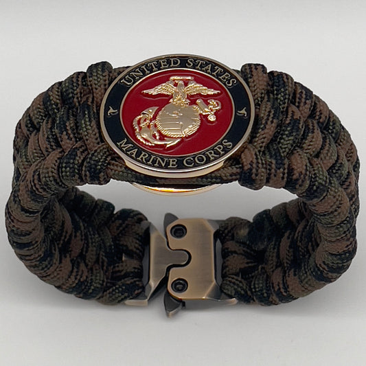 Thick, wide, semi-rigid and comfortable braided United States Marine Corps bracelet featuring a 24K gold plated USMC Eagle Globe and Anchor medallion, a gold Cobra style tactical buckle and woven with Woodland Camo 550 paracord.