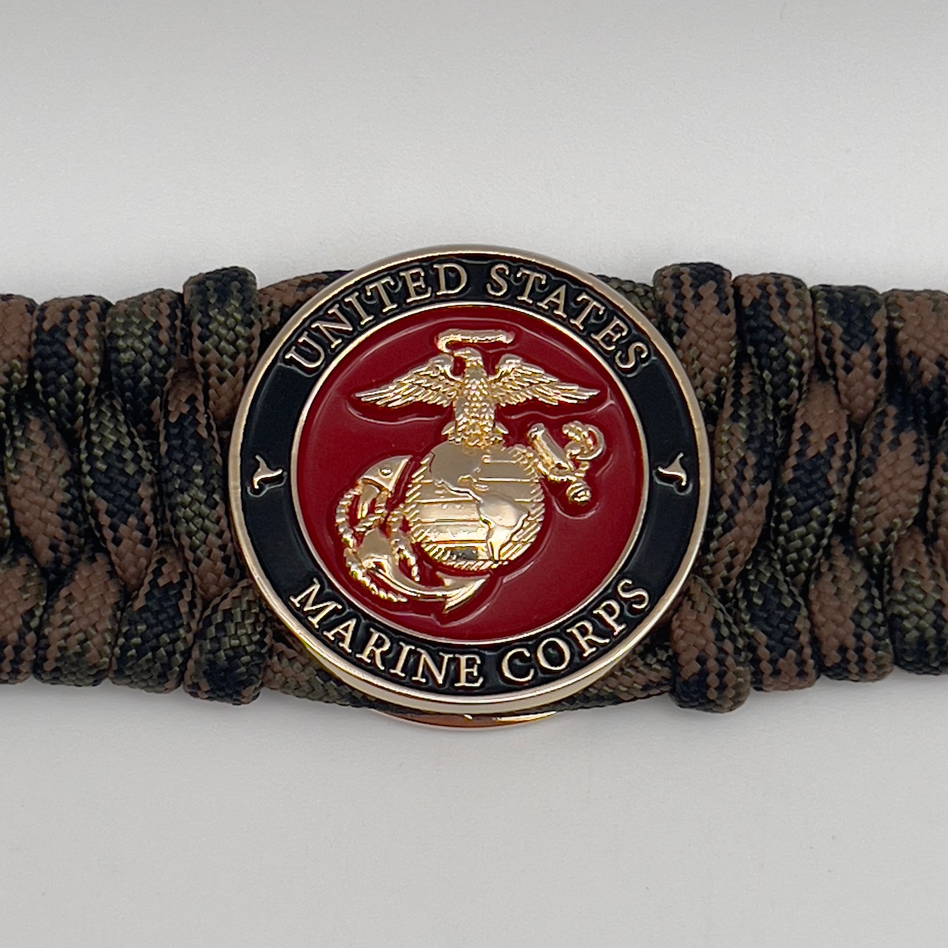 Thick, wide, semi-rigid and comfortable braided United States Marine Corps bracelet featuring a 24K gold plated USMC Eagle Globe and Anchor medallion, a gold Cobra style tactical buckle and woven with Woodland Camo 550 paracord.