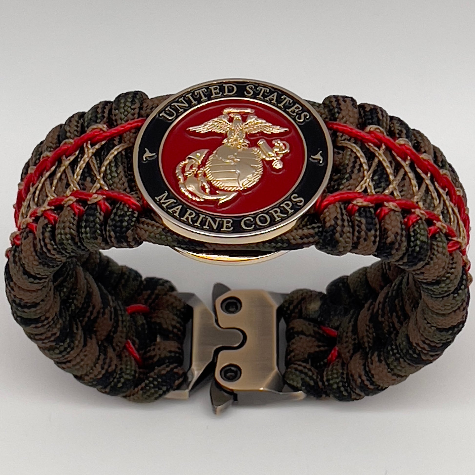 Thick, wide, rigid and comfortable braided United States Marine Corps bracelet featuring a 24K gold plated USMC Eagle Globe and Anchor medallion, a gold Cobra style tactical buckle and woven with Woodland Camo 550 paracord and Imperial Red micro and gold nano cord.