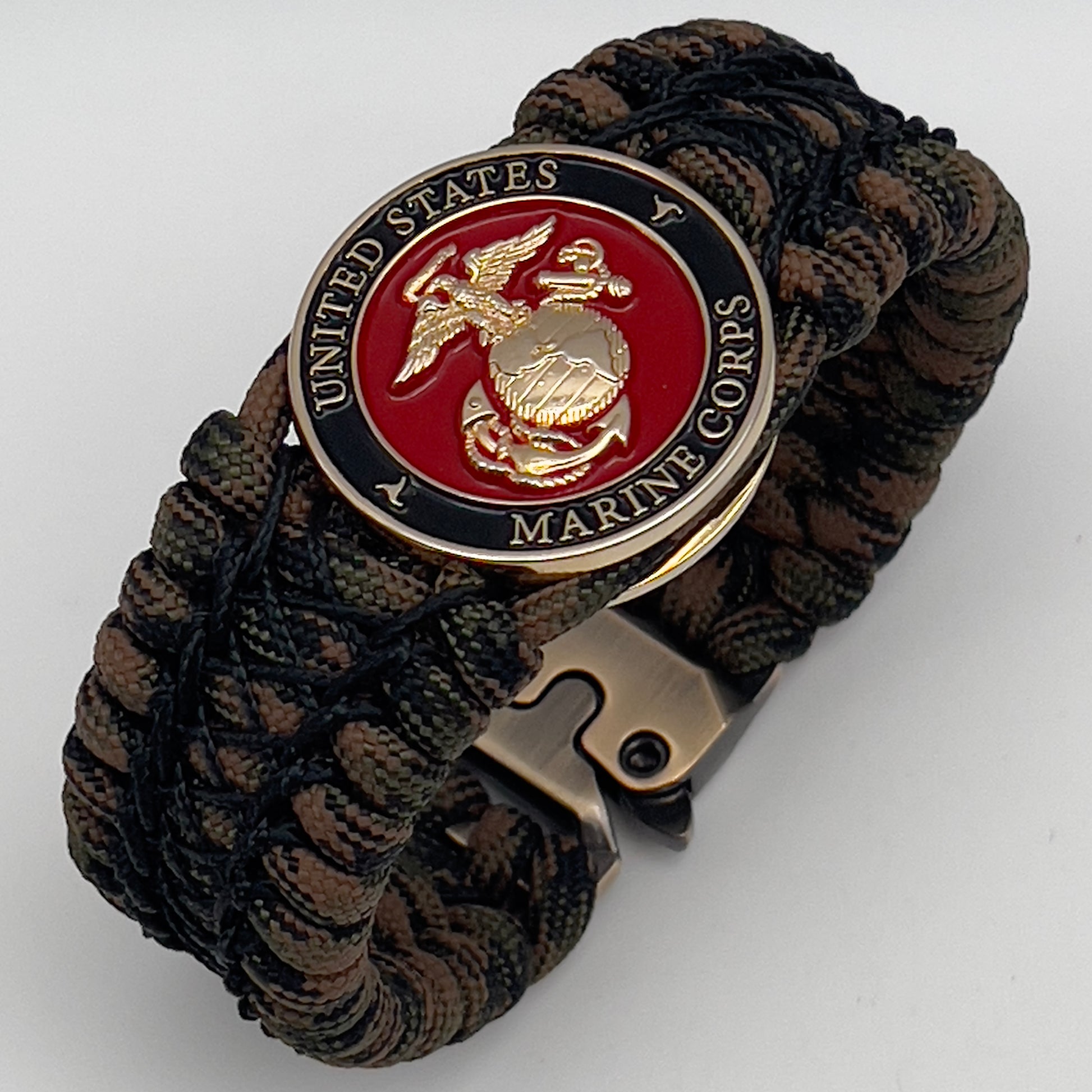 Thick, wide, rigid and comfortable braided United States Marine Corps bracelet featuring a 24K gold plated USMC Eagle Globe and Anchor medallion, a gold Cobra style tactical buckle and woven with Woodland Camo 550 paracord and black nano and micro cord.