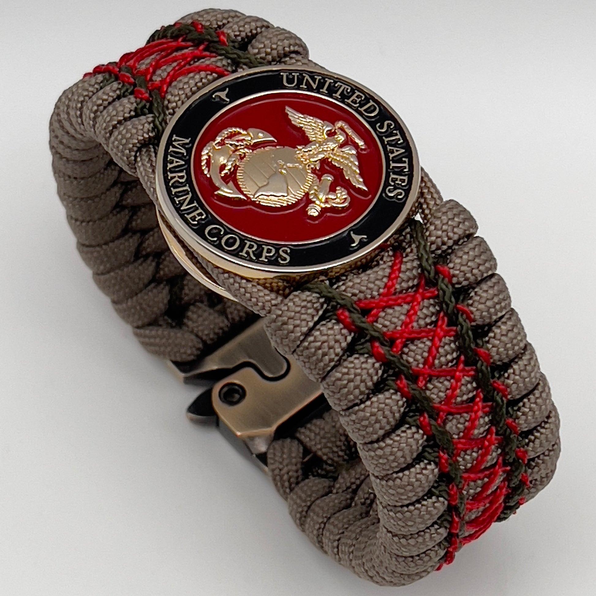 Thick, wide, rigid and comfortable braided United States Marine Corps bracelet featuring a 24K gold plated USMC Eagle Globe and Anchor medallion, a gold Cobra style tactical buckle and woven with tan 550 paracord, olive drab micro and Imperial red nano cord.