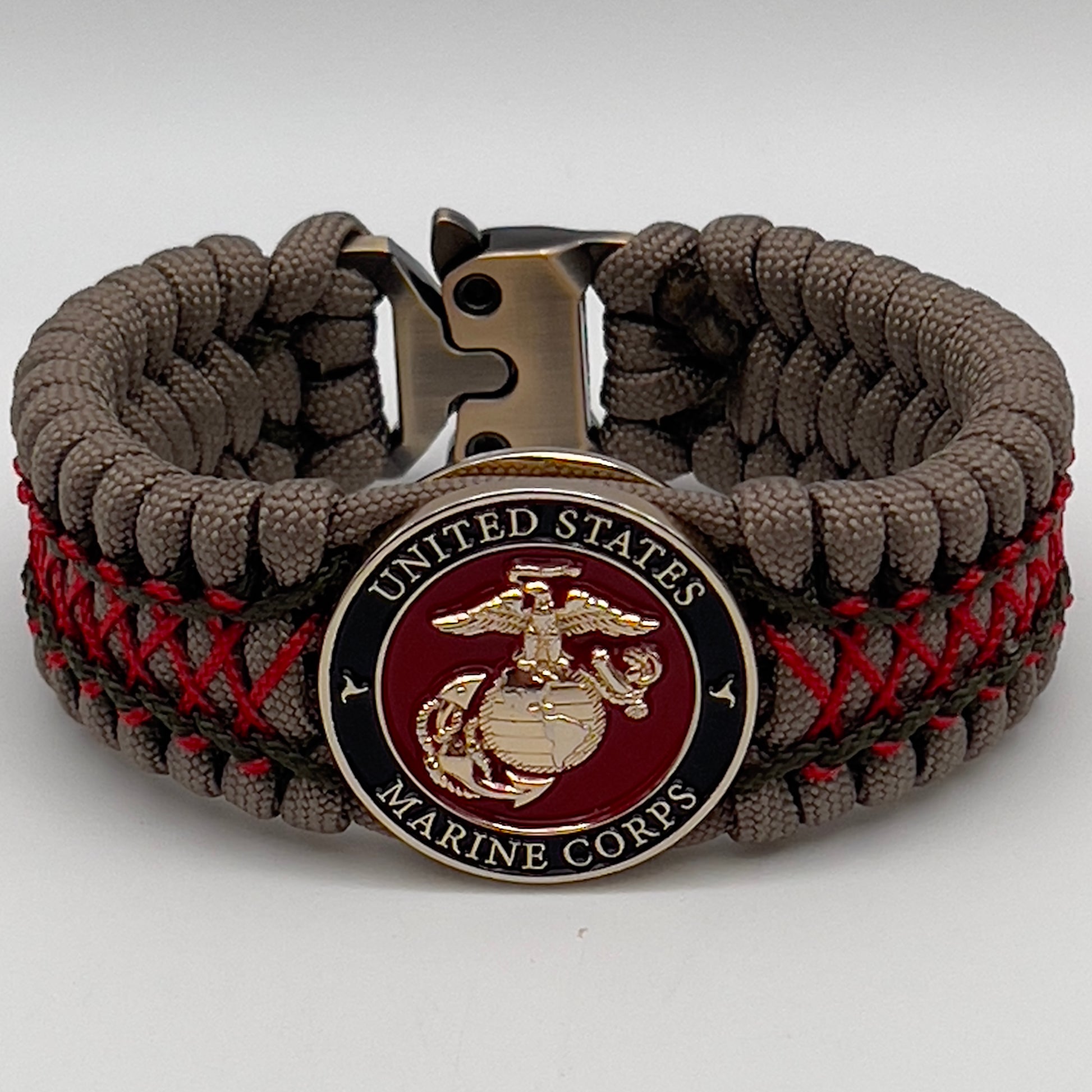Thick, wide, rigid and comfortable braided United States Marine Corps bracelet featuring a 24K gold plated USMC Eagle Globe and Anchor medallion, a gold Cobra style tactical buckle and woven with tan 550 paracord, olive drab micro and Imperial red nano cord.