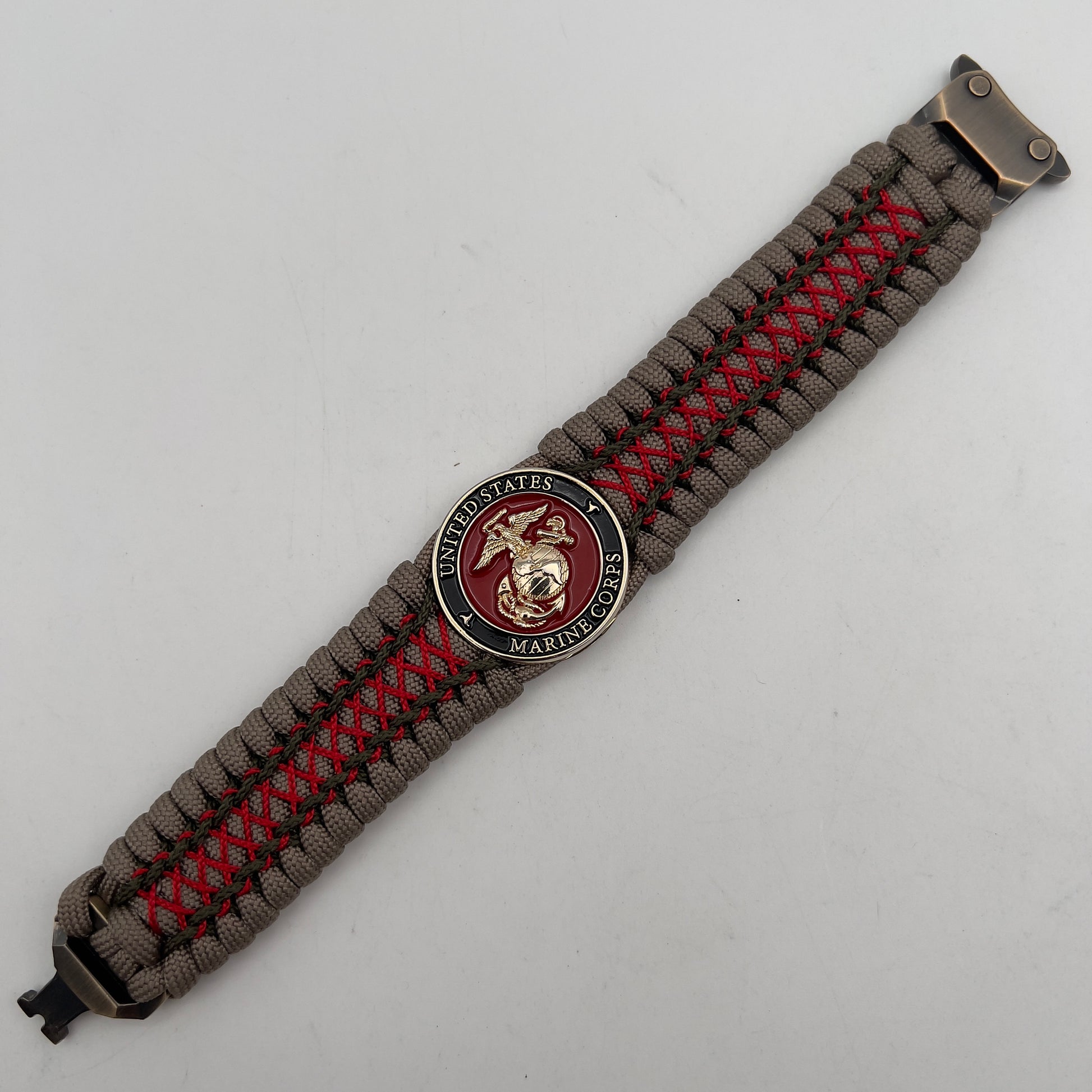 Thick, wide, rigid and comfortable braided United States Marine Corps bracelet featuring a 24K gold plated USMC Eagle Globe and Anchor medallion, a gold Cobra style tactical buckle and woven with tan 550 paracord, olive drab micro and Imperial red nano cord.