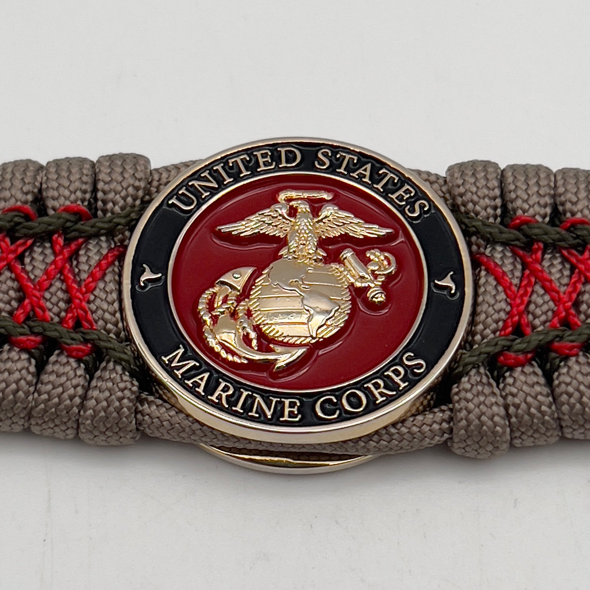 Thick, wide, rigid and comfortable braided United States Marine Corps bracelet featuring a 24K gold plated USMC Eagle Globe and Anchor medallion, a gold Cobra style tactical buckle and woven with tan 550 paracord, olive drab micro and Imperial red nano cord.
