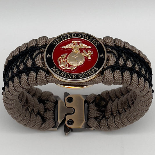Thick, wide, rigid and comfortable braided United States Marine Corps bracelet featuring a 24K gold plated USMC Eagle Globe and Anchor medallion, a gold Cobra style tactical buckle and woven with tan 550 paracord and black nano and micro cord.
