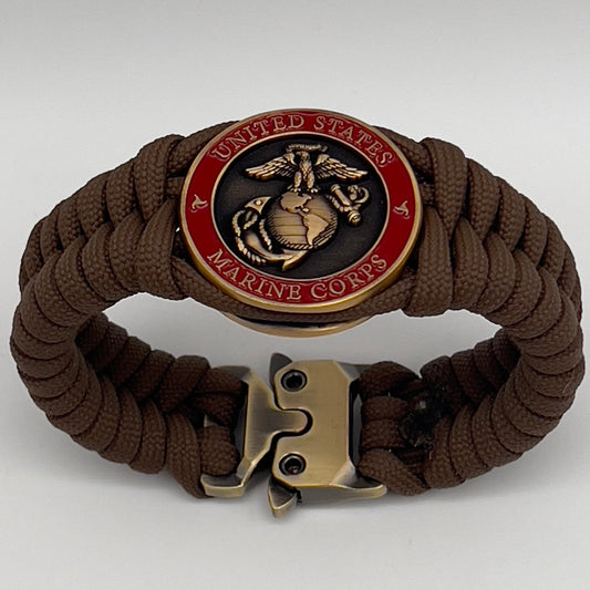Thick, medium width, semi-rigid and comfortable braided United States Marine Corps bracelet featuring a 24K antique gold plated USMC Eagle Globe and Anchor medallion, a gold Cobra style tactical buckle and woven with Coyote Brown 550 paracord 
