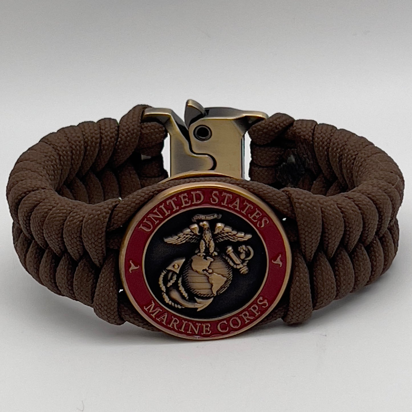 Thick, medium width, semi-rigid and comfortable braided United States Marine Corps bracelet featuring a 24K antique gold plated USMC Eagle Globe and Anchor medallion, a gold Cobra style tactical buckle and woven with Coyote Brown 550 paracord 
