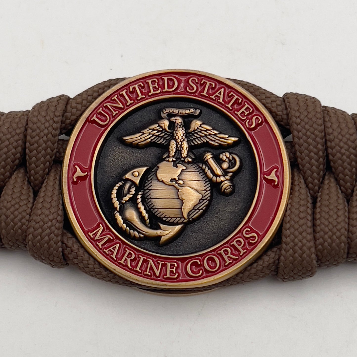 Thick, medium width, semi-rigid and comfortable braided United States Marine Corps bracelet featuring a 24K antique gold plated USMC Eagle Globe and Anchor medallion, a gold Cobra style tactical buckle and woven with Coyote Brown 550 paracord 