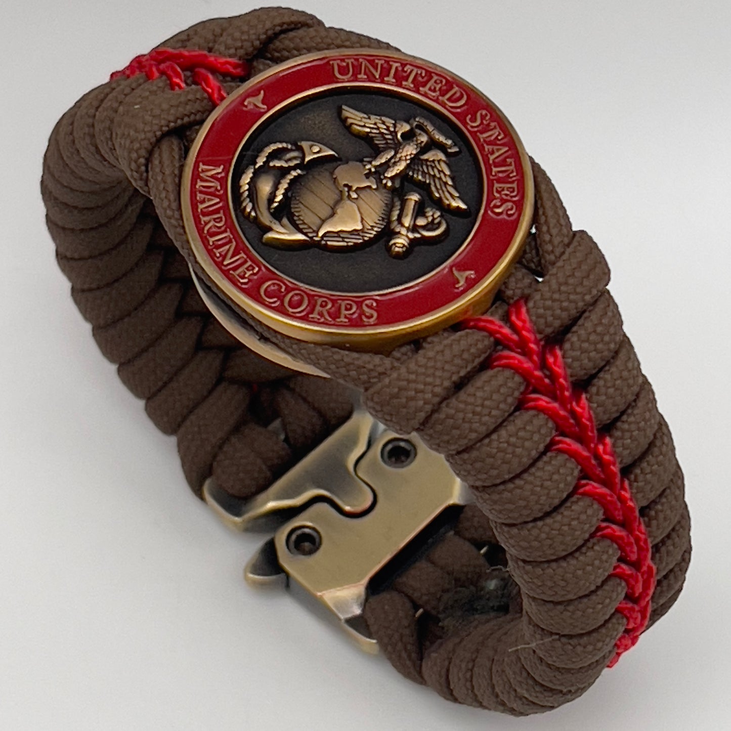 Thick, medium width, semi-rigid and comfortable braided United States Marine Corps bracelet featuring a 24K antique gold plated USMC Eagle Globe and Anchor medallion, a gold Cobra style tactical buckle and woven with Coyote Brown 550 paracord and Imperial Red micro cord.