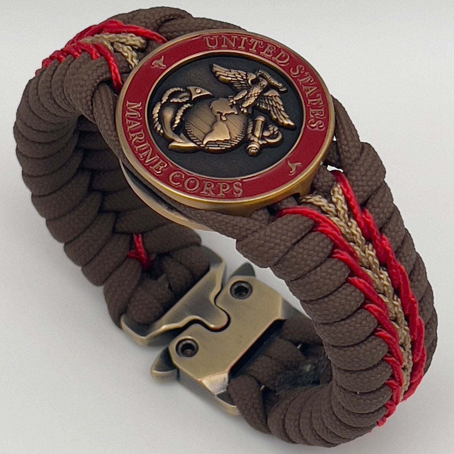 Thick, medium width, rigid and comfortable braided United States Marine Corps bracelet featuring a 24K antique gold plated USMC Eagle Globe and Anchor medallion, a gold Cobra style tactical buckle and woven with Coyote Brown 550 paracord and Imperial Red and Gold micro cord.