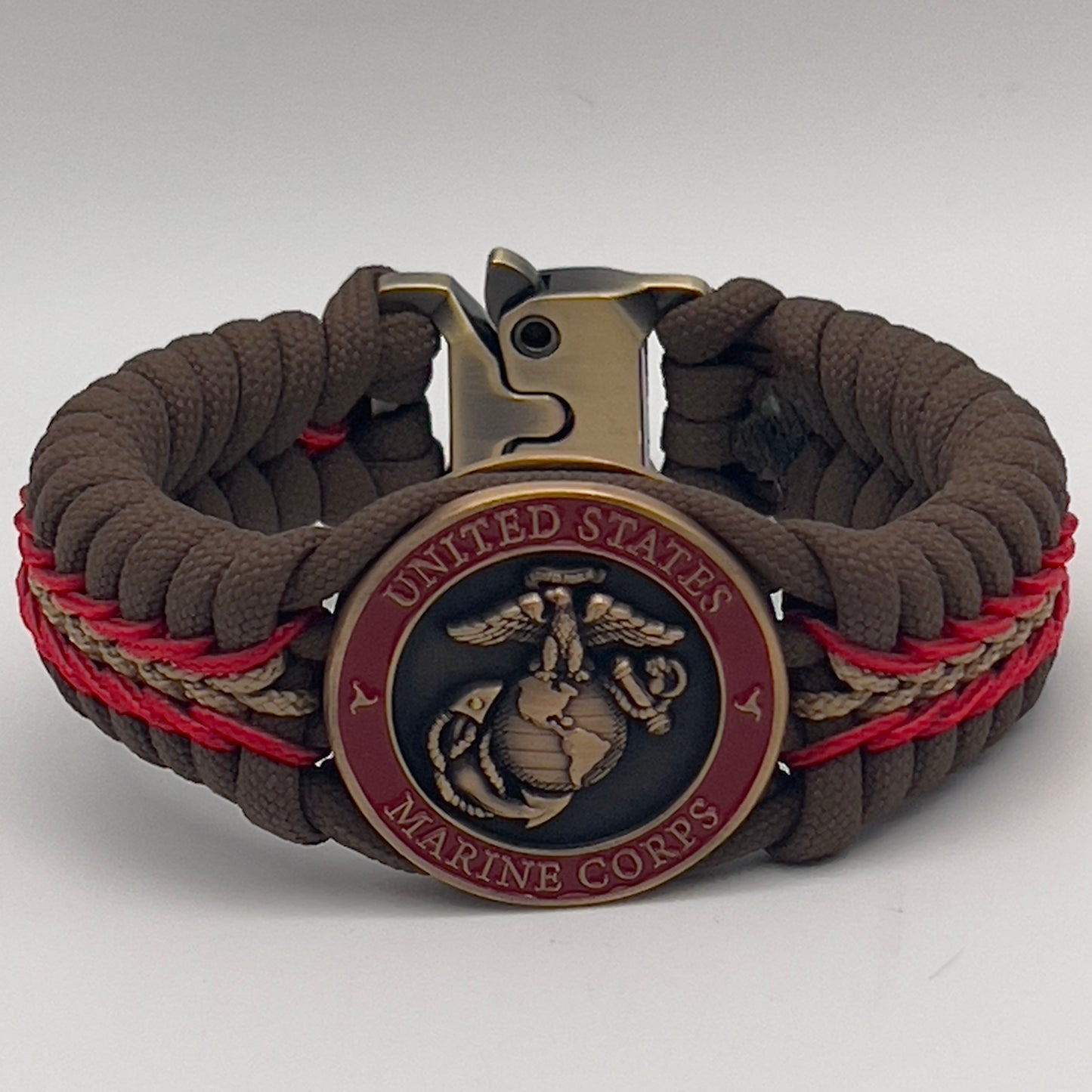 Thick, medium width, rigid and comfortable braided United States Marine Corps bracelet featuring a 24K antique gold plated USMC Eagle Globe and Anchor medallion, a gold Cobra style tactical buckle and woven with Coyote Brown 550 paracord and Imperial Red and Gold micro cord.