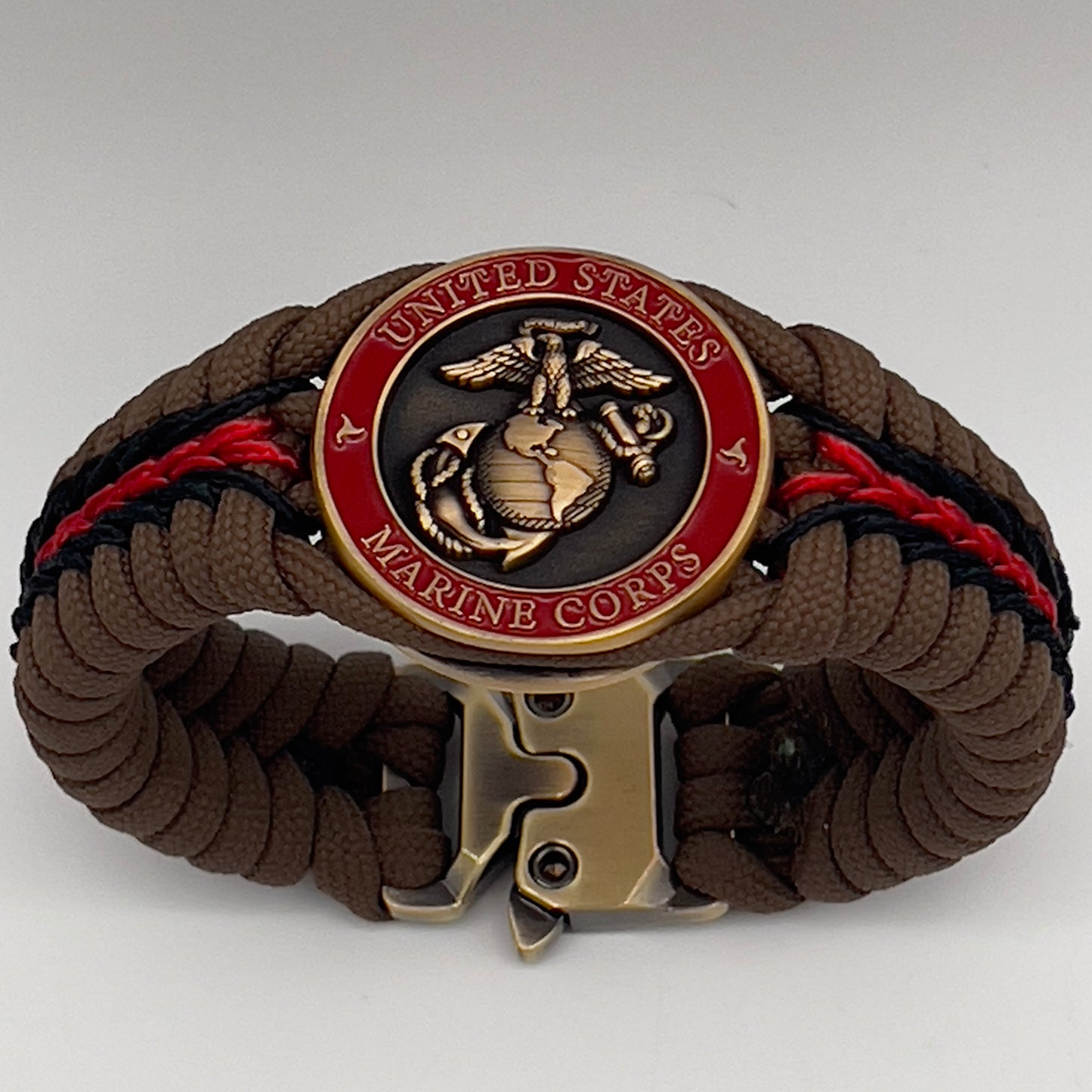 Thick, medium width, rigid and comfortable braided United States Marine Corps bracelet featuring a 24K antique gold plated USMC Eagle Globe and Anchor medallion, a gold Cobra style tactical buckle and woven with Coyote Brown 550 paracord and Imperial Red and Black micro cord.