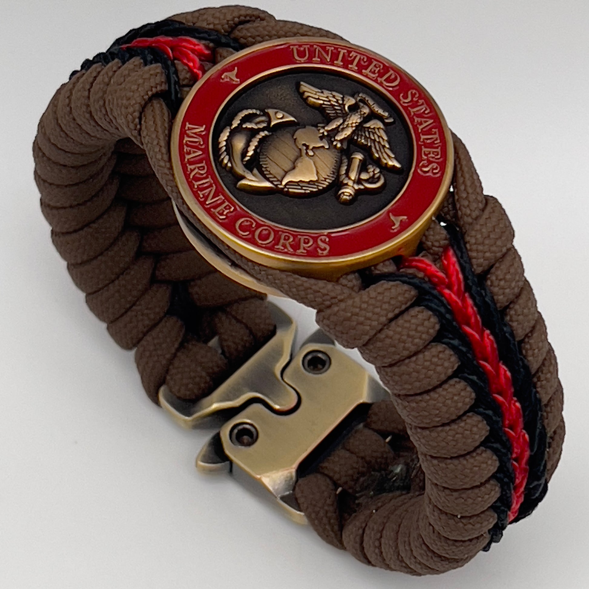 Thick, medium width, rigid and comfortable braided United States Marine Corps bracelet featuring a 24K antique gold plated USMC Eagle Globe and Anchor medallion, a gold Cobra style tactical buckle and woven with Coyote Brown 550 paracord and Imperial Red and Black micro cord.