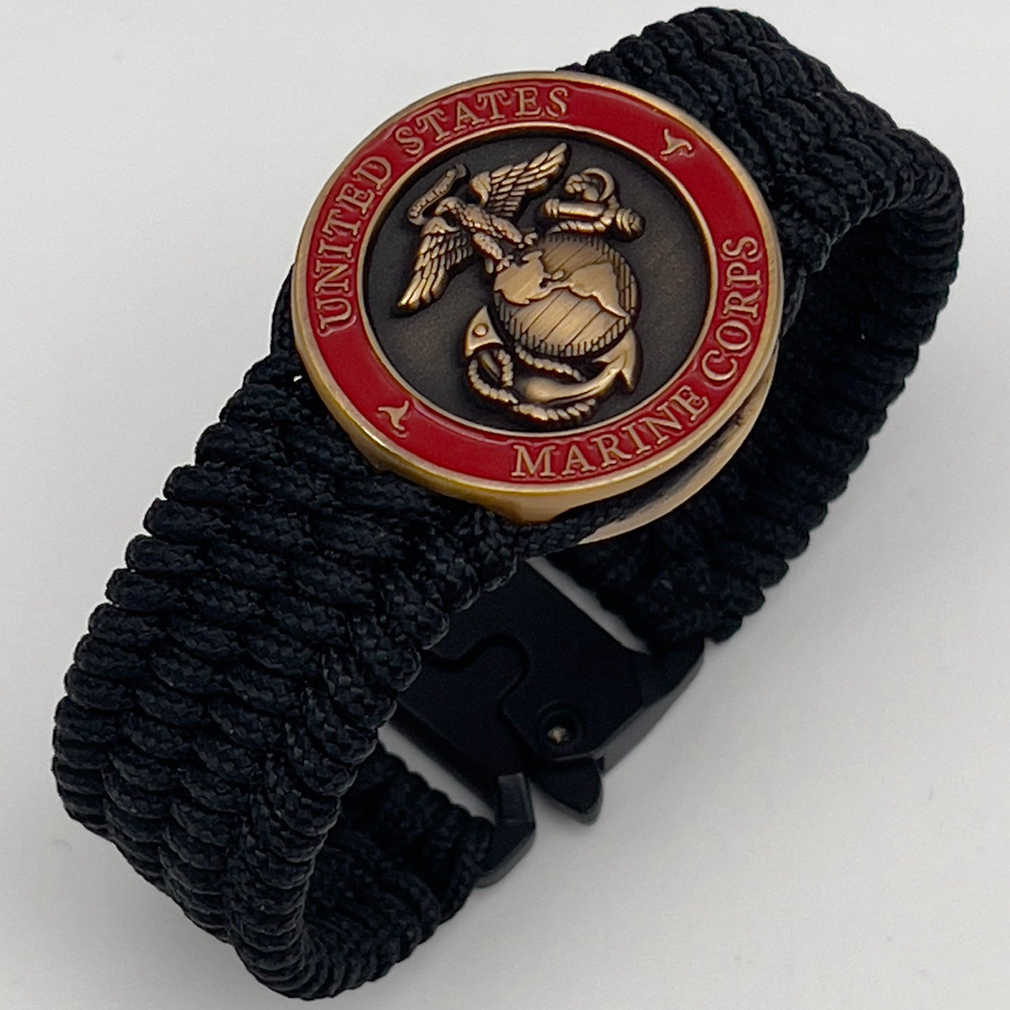 Thin, medium wide, very thin and flexible and comfortable braided United States Marine Corps bracelet featuring a 24K antique gold plated USMC Eagle Globe and Anchor medallion, a black Cobra style tactical buckle and woven with black Type-1 paracord.