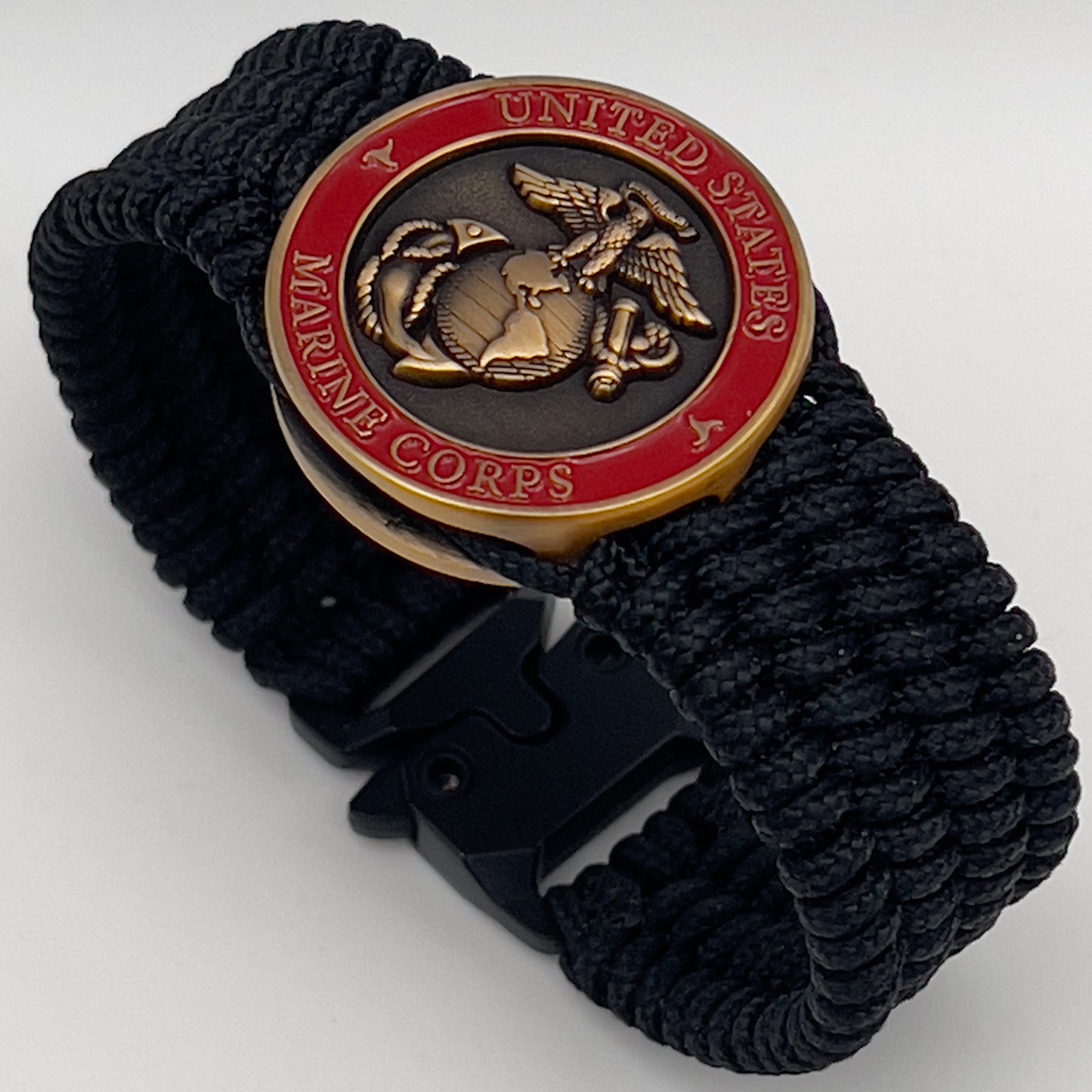Thin, medium wide, very thin and flexible and comfortable braided United States Marine Corps bracelet featuring a 24K antique gold plated USMC Eagle Globe and Anchor medallion, a black Cobra style tactical buckle and woven with black Type-1 paracord.