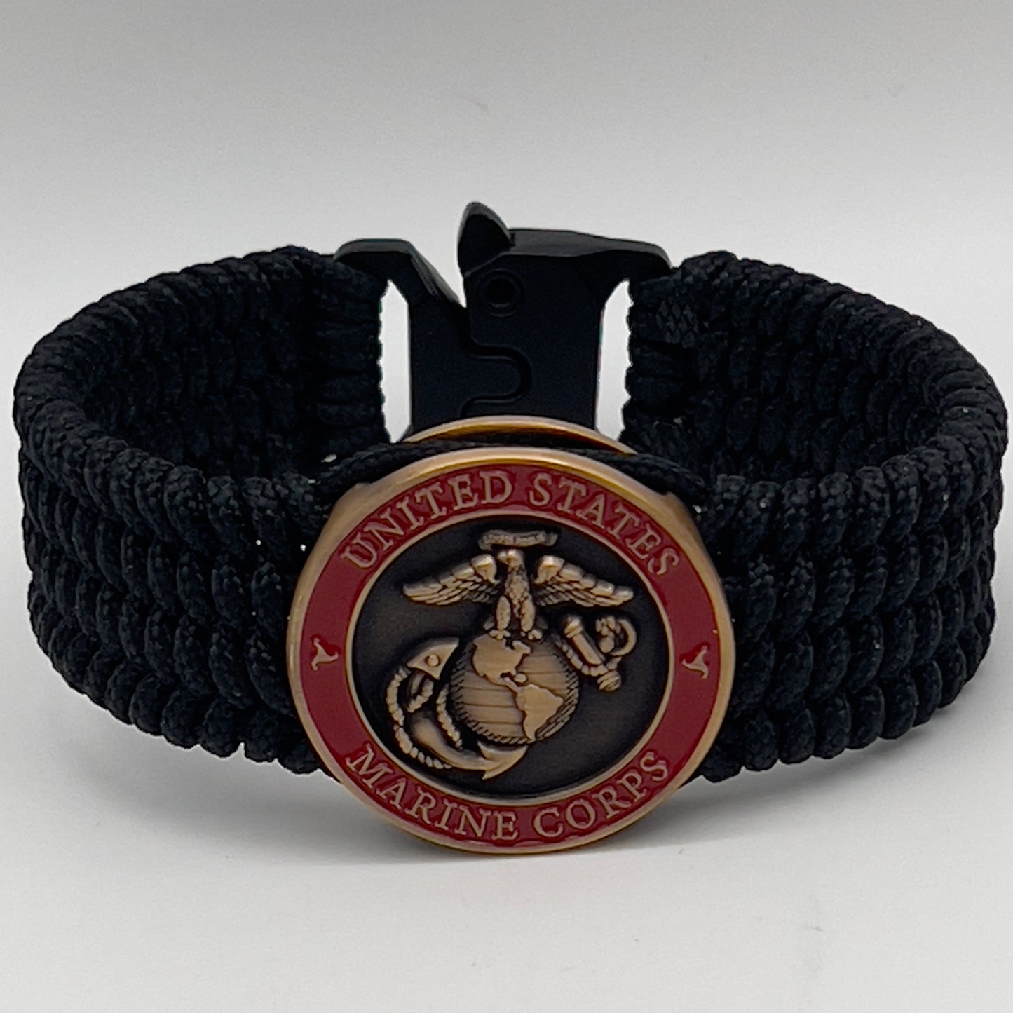 Thin, medium wide, very thin and flexible and comfortable braided United States Marine Corps bracelet featuring a 24K antique gold plated USMC Eagle Globe and Anchor medallion, a black Cobra style tactical buckle and woven with black Type-1 paracord.
