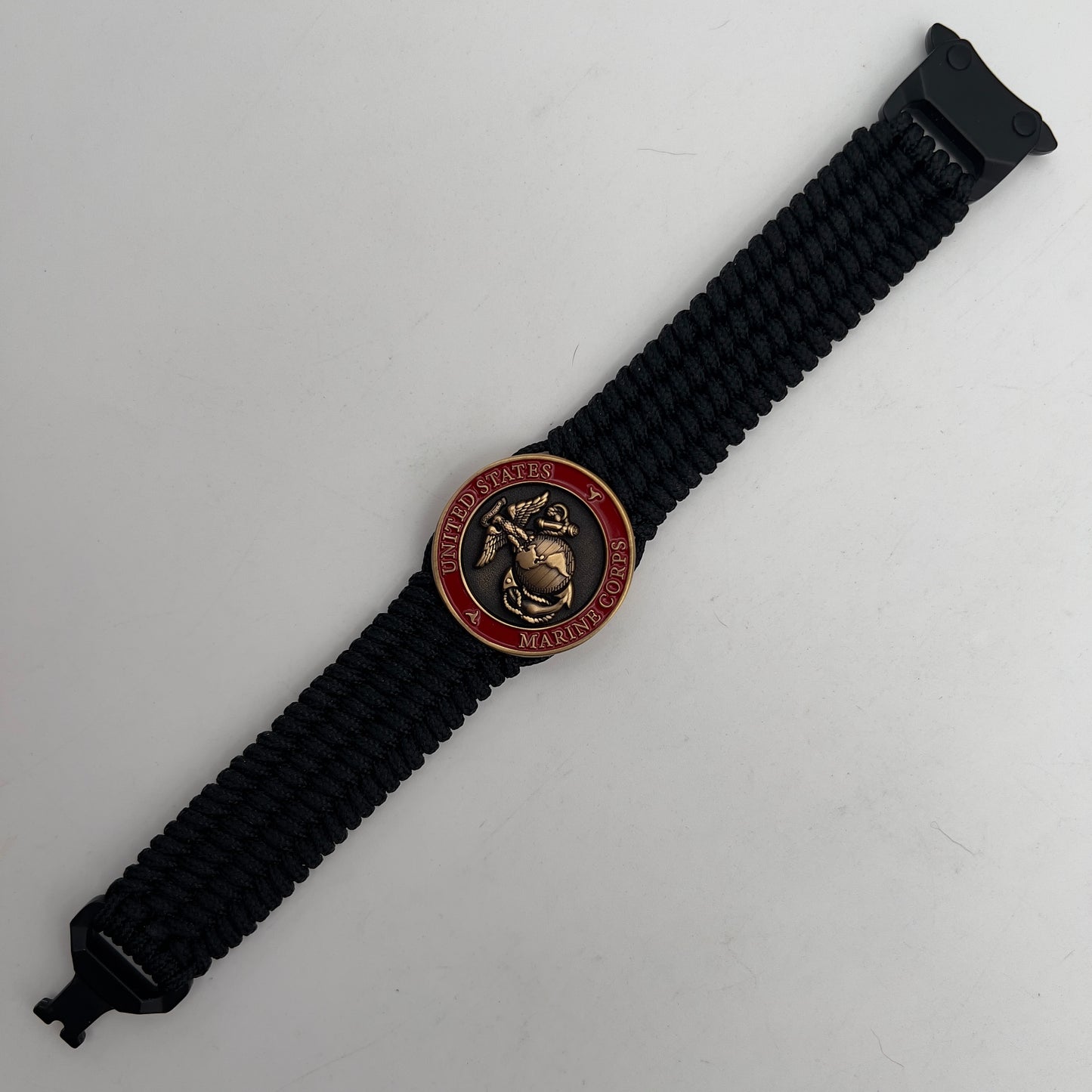 Thin, medium wide, very thin and flexible and comfortable braided United States Marine Corps bracelet featuring a 24K antique gold plated USMC Eagle Globe and Anchor medallion, a black Cobra style tactical buckle and woven with black Type-1 paracord.