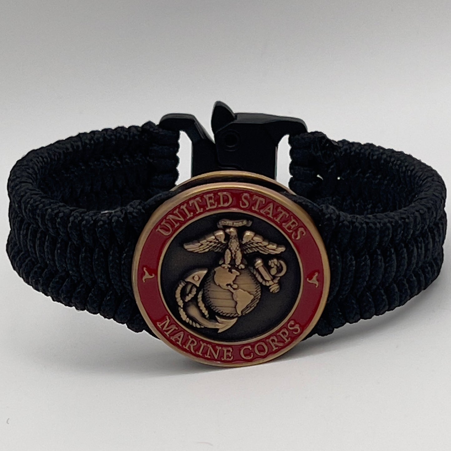 Thin, narrow, flexible and comfortable braided United States Marine Corps bracelet featuring a 24K antique gold plated USMC Eagle Globe and Anchor medallion, a black Cobra style tactical buckle and woven with black Type-1 paracord.