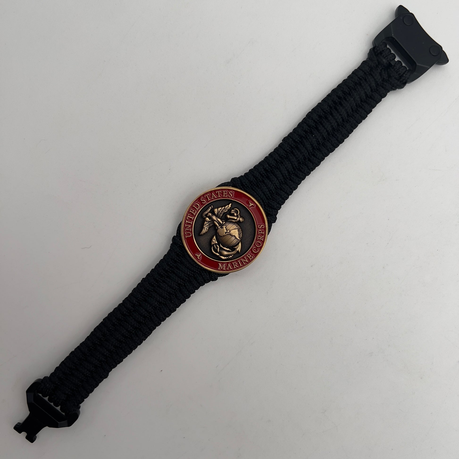 Thin, narrow, flexible and comfortable braided United States Marine Corps bracelet featuring a 24K antique gold plated USMC Eagle Globe and Anchor medallion, a black Cobra style tactical buckle and woven with black Type-1 paracord.