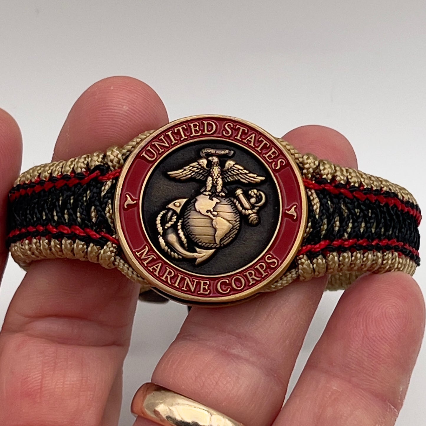 Thin, narrow, very thin and flexible and comfortable braided United States Marine Corps bracelet featuring a 24K antique gold plated USMC Eagle Globe and Anchor medallion, a gold Cobra style tactical buckle and woven with gold Type-1 paracord and Imperial Red and Black nano cord.